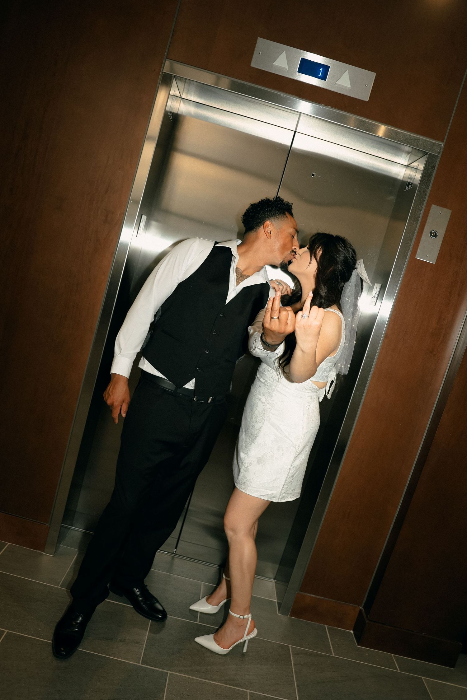 A couple embracing and kissing near an elevator entrance.