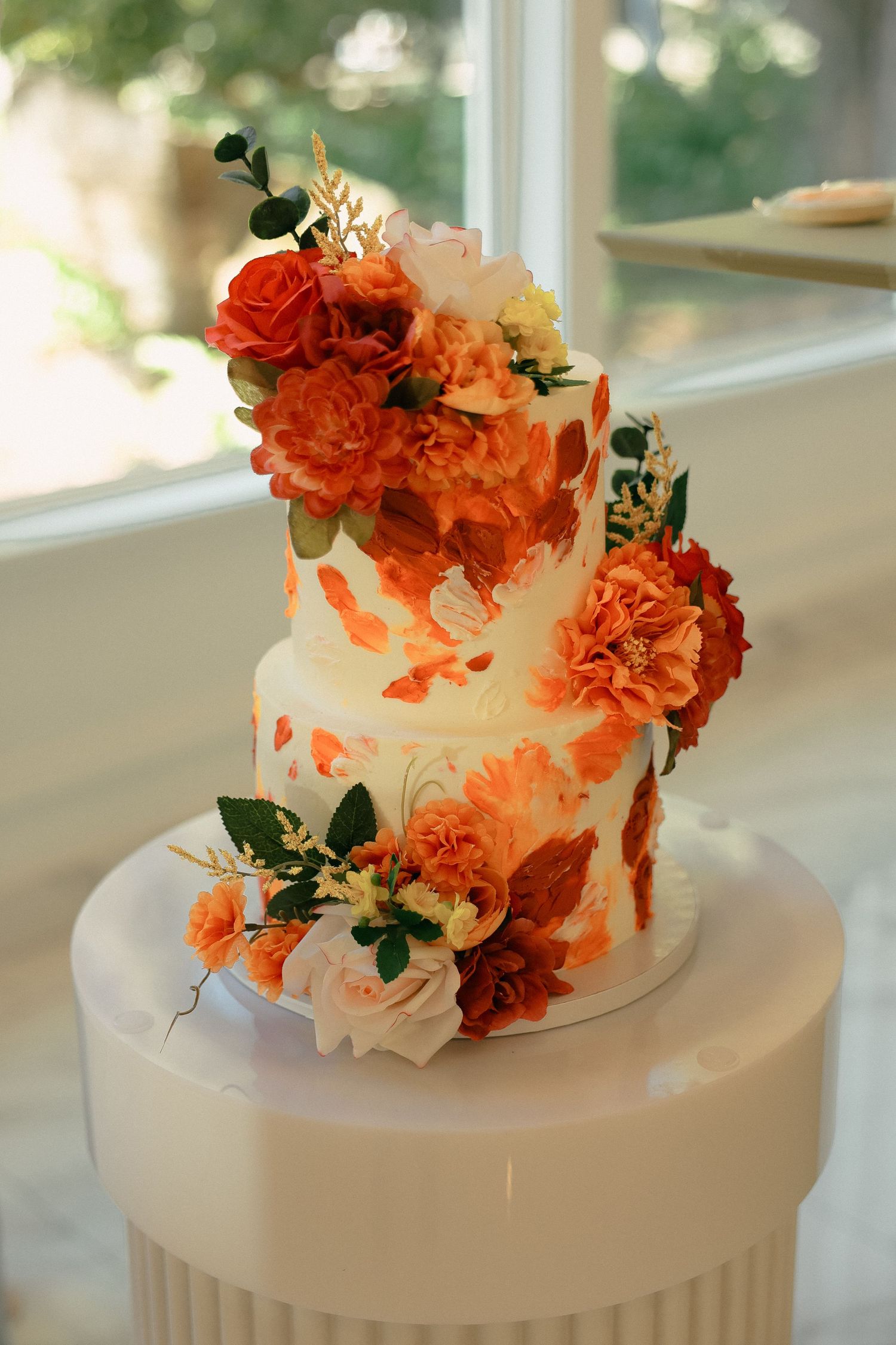 Wedding cake decorated with cascading orange and coral flowers on white fondant.