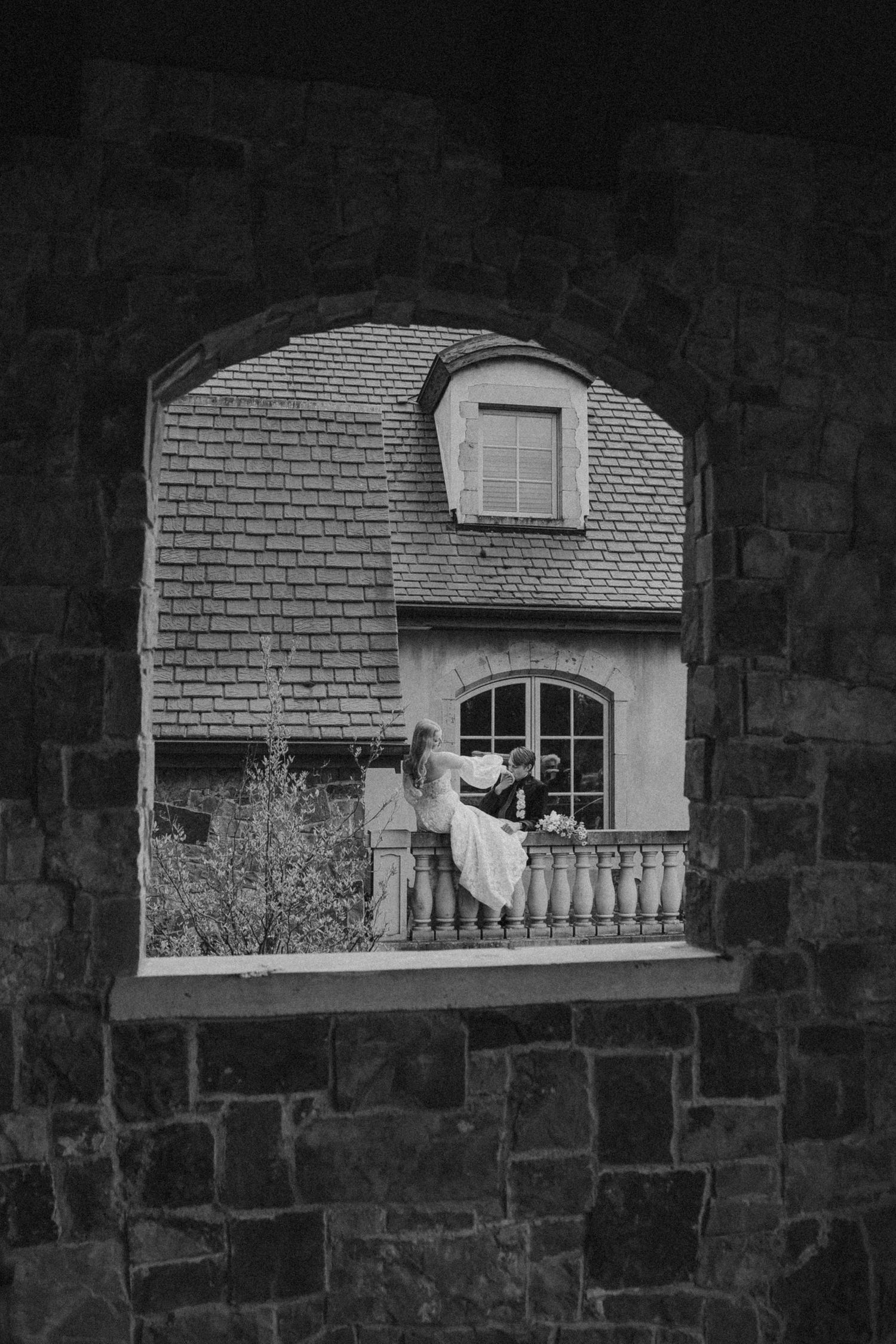 Artistic black and white photos through stone window frames at wedding venue.