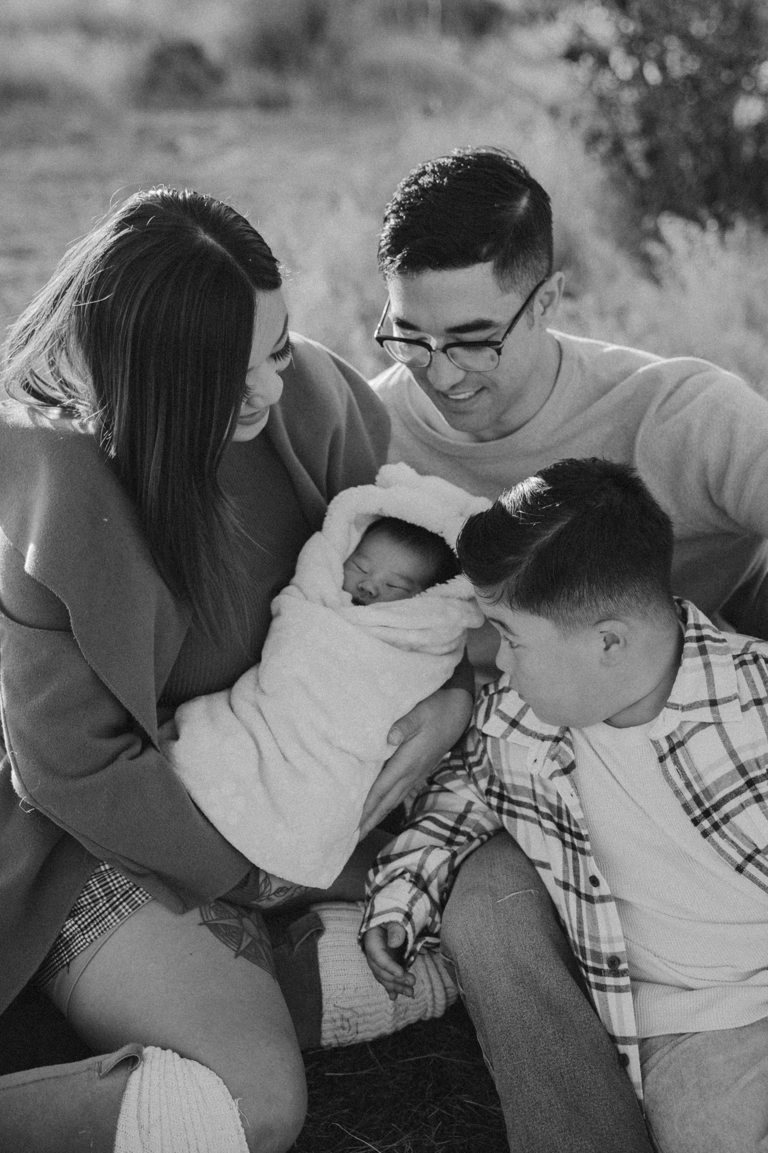 A loving family shares an intimate moment together outdoors in black and white photography.