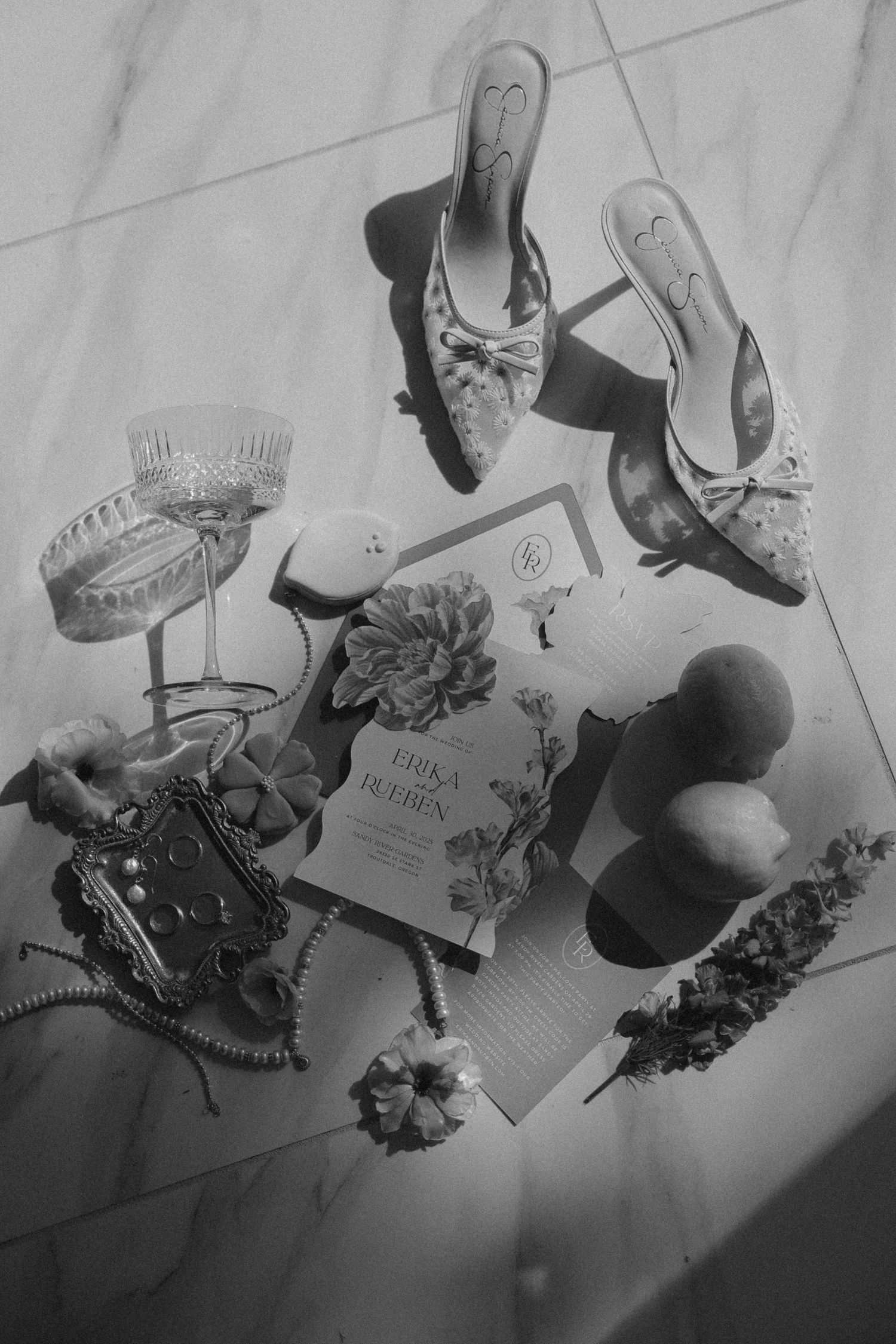 Wedding day accessories arranged in black and white including shoes, jewelry and floral elements.