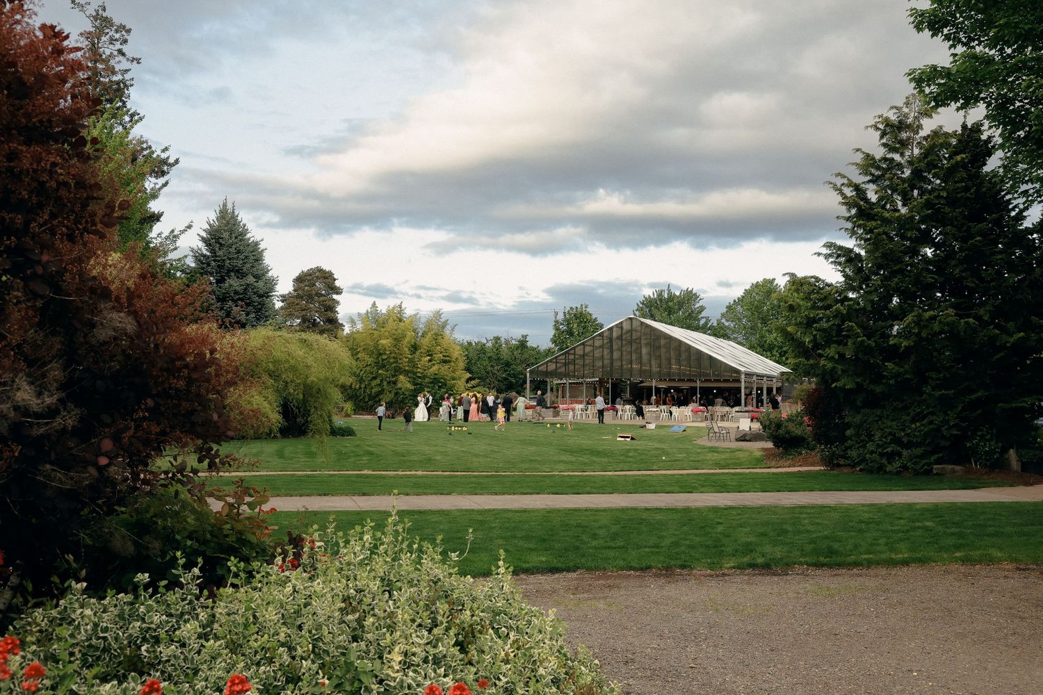 Panoramic view of an outdoor wedding venue with green lawn and cloudy sky.