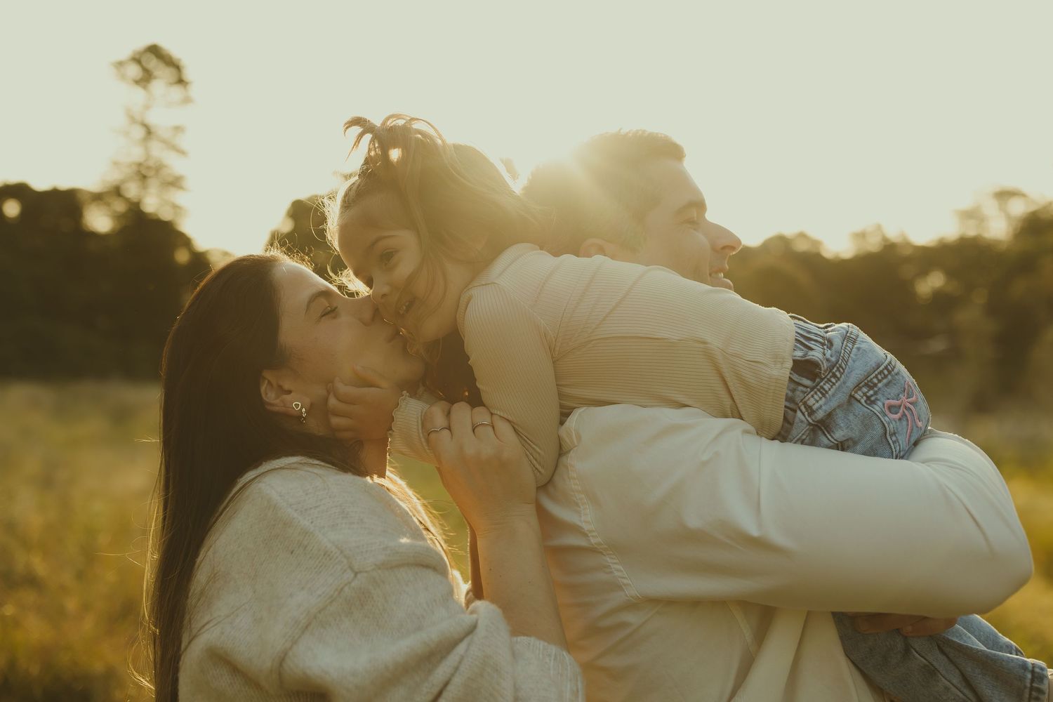 A loving family embraces in a sun-drenched meadow during golden hour, creating a heartwarming silhouette against nature.