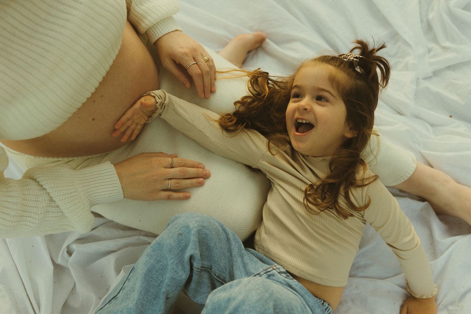 Playful sequence showing joyful interactions on a white bed in natural lighting.