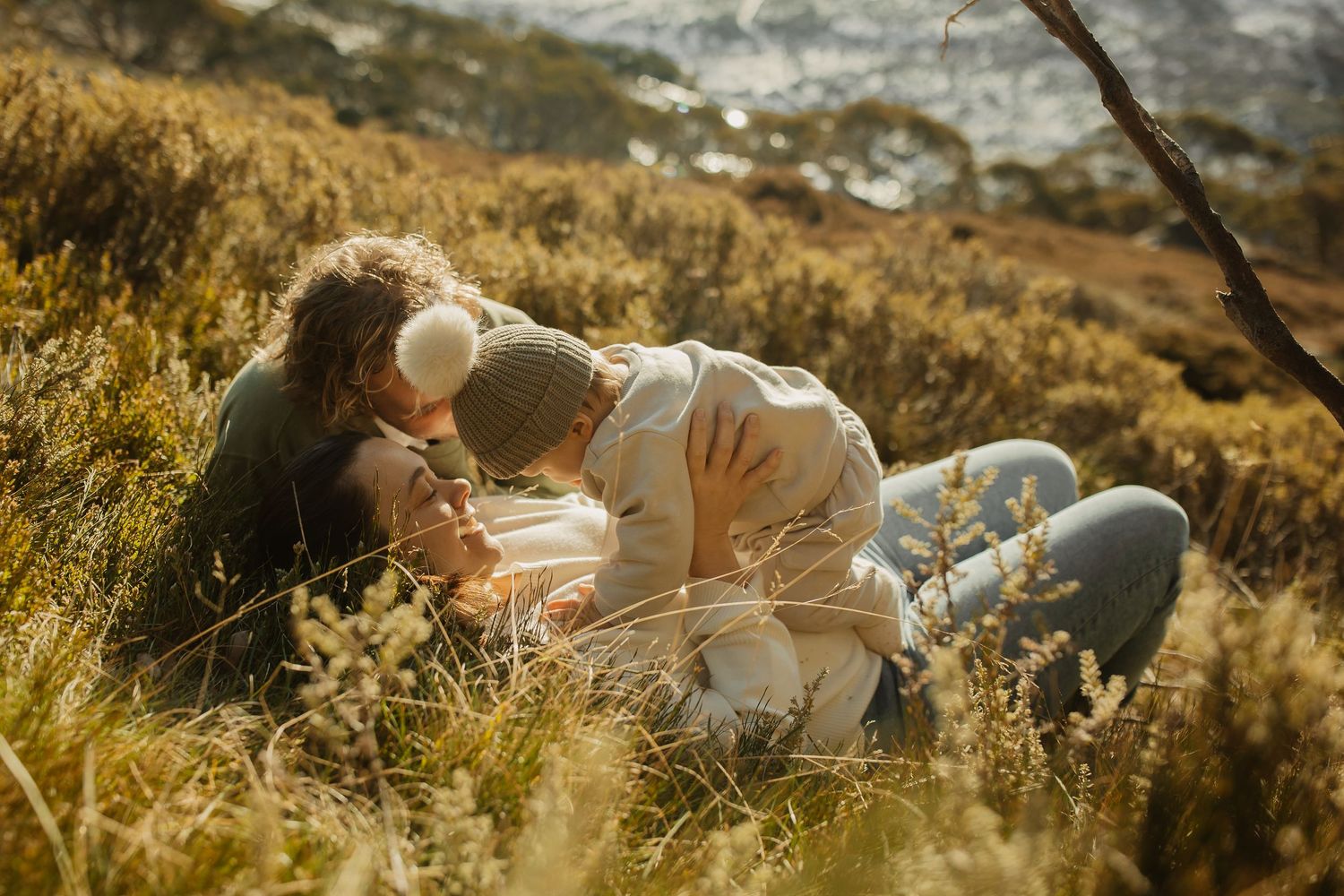 Couple relaxing together in golden grass field on sunny mountainside.