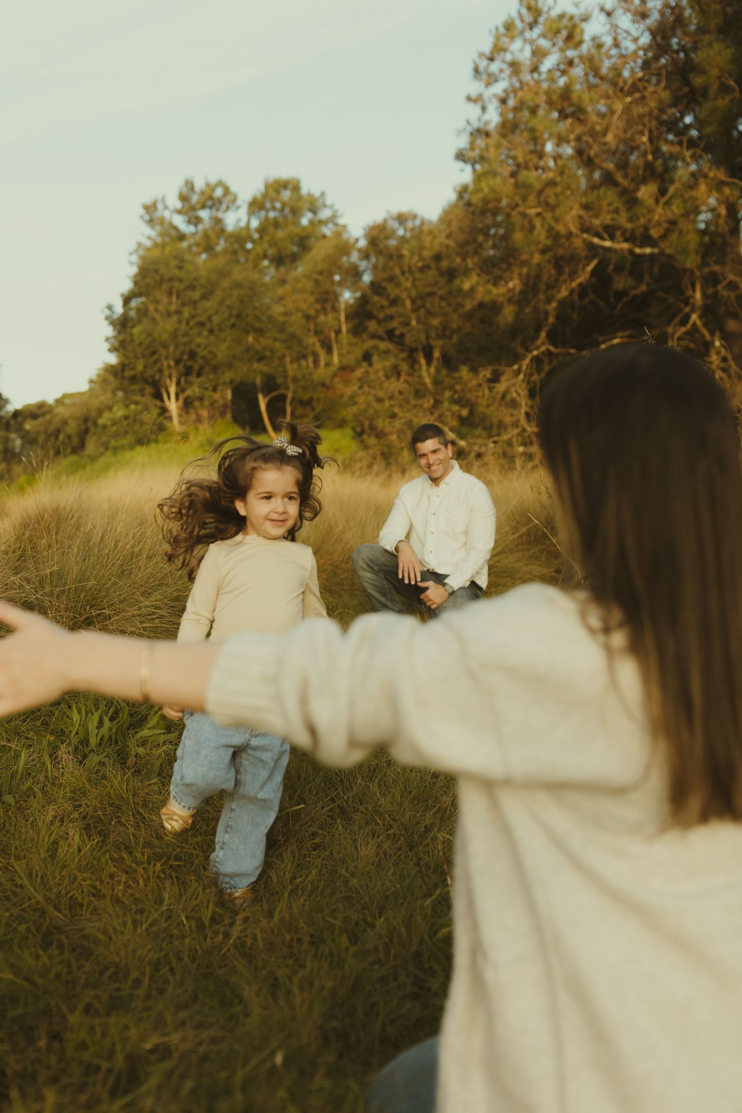 A playful moment captured between two people in casual attire on a grassy hillside at sunset.