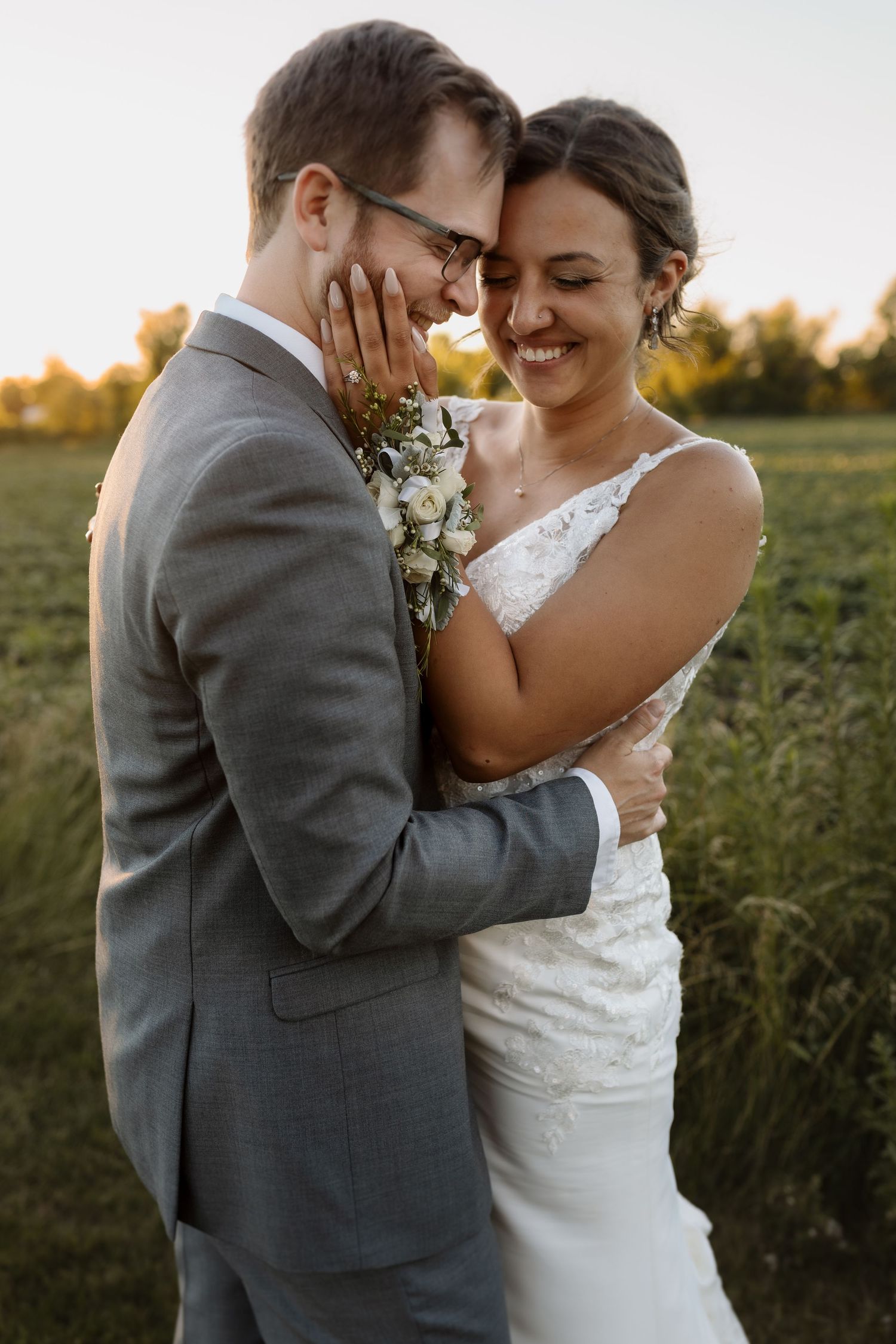A romantic sunset moment between newlyweds in a field.