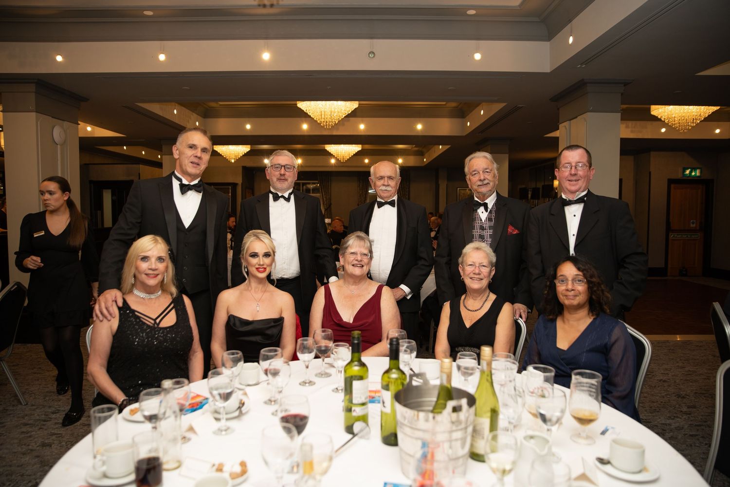 A group of people in formal evening wear at a corporate gala event photography in Grays, Essex. captured in a well lit function room