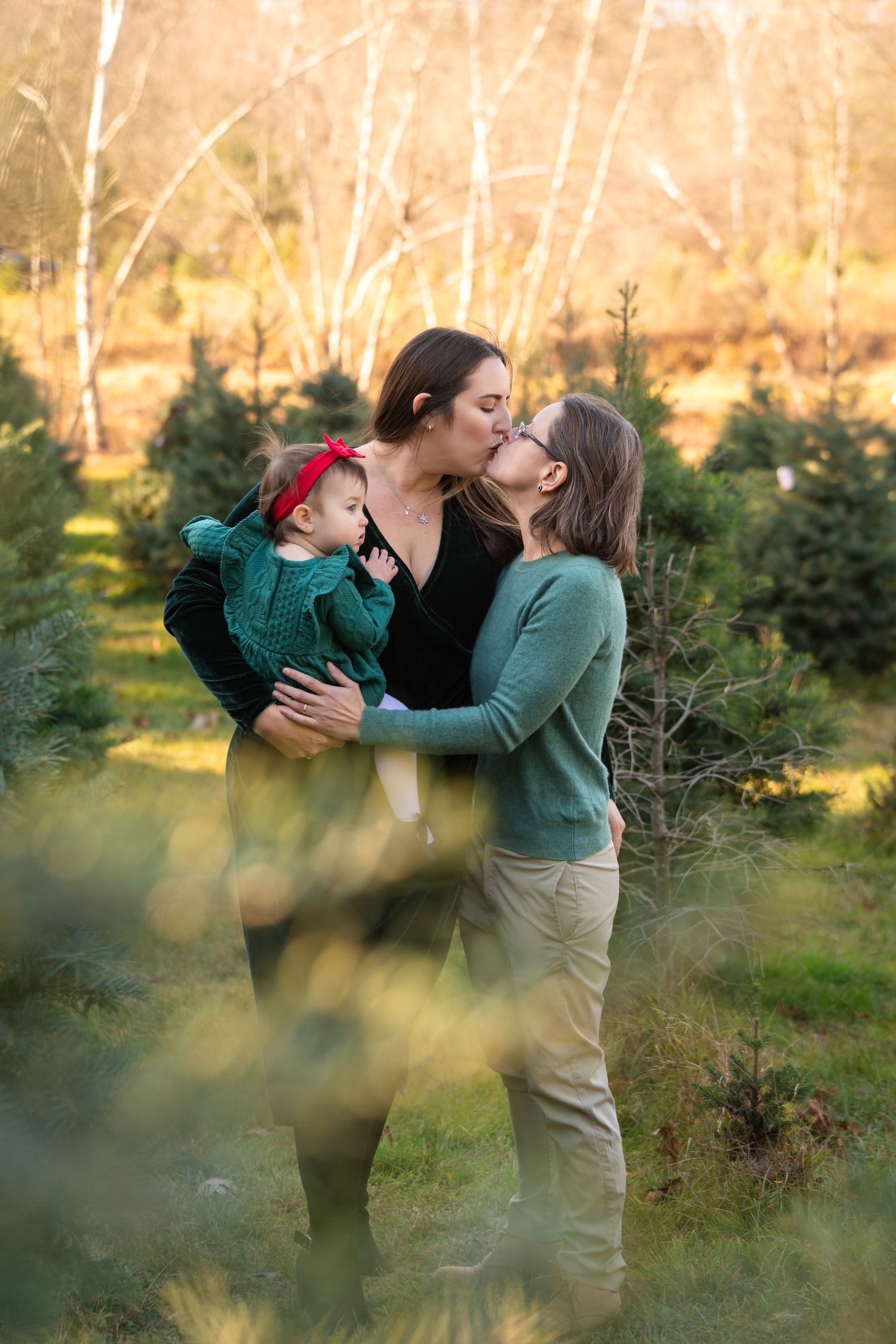 Intimate family moment captured amongst evergreen trees on a sunny autumn day.