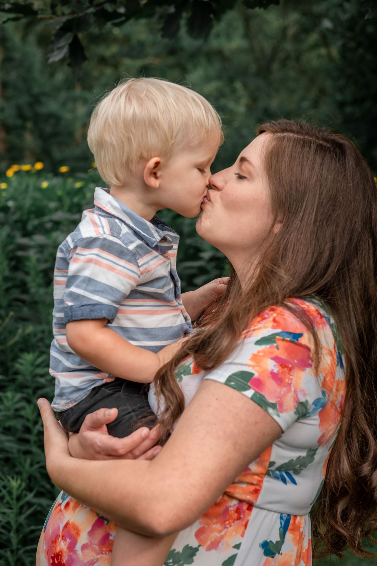 A tender moment shared between parent and child in a garden setting with flowers in the background.