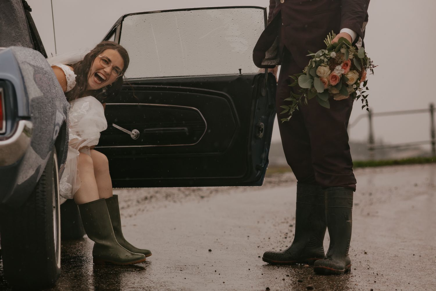 Casual moment with wellies by vintage car door during wedding photoshoot.