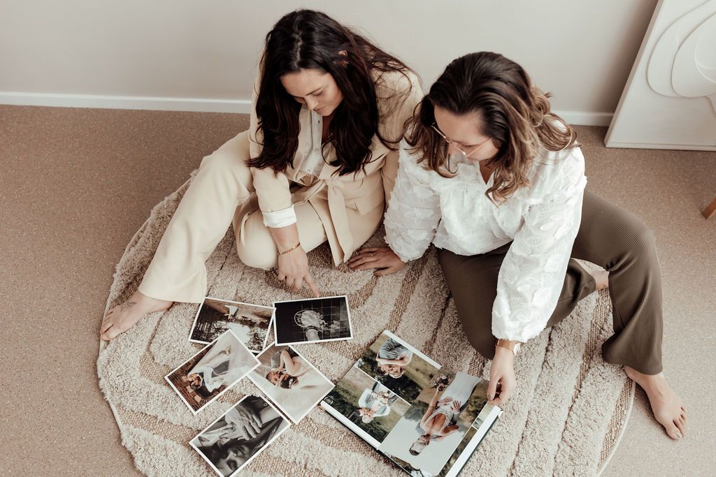 Two people sitting on carpet looking through photo albums together.