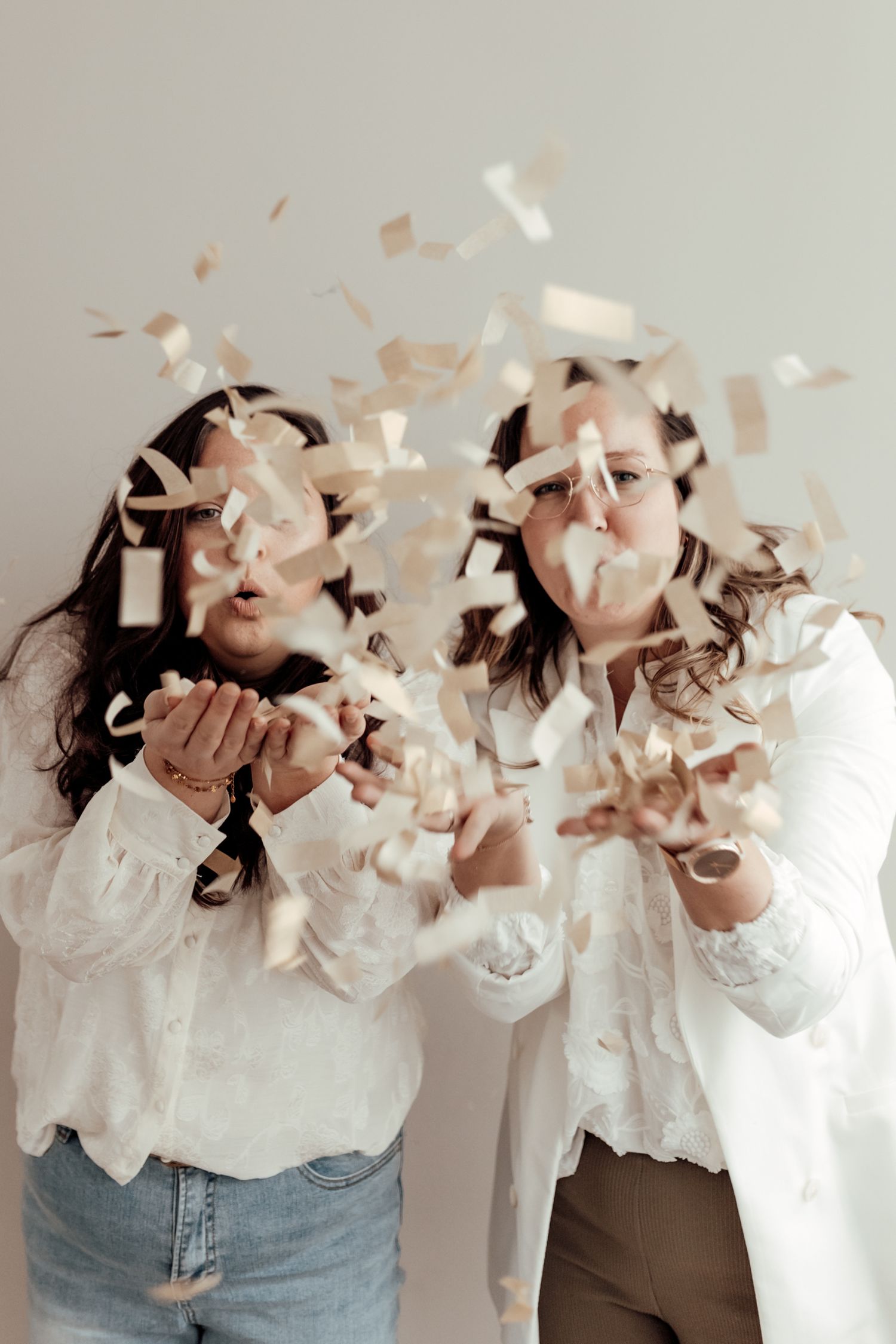 Friends blowing confetti and laughing in a carefree moment.