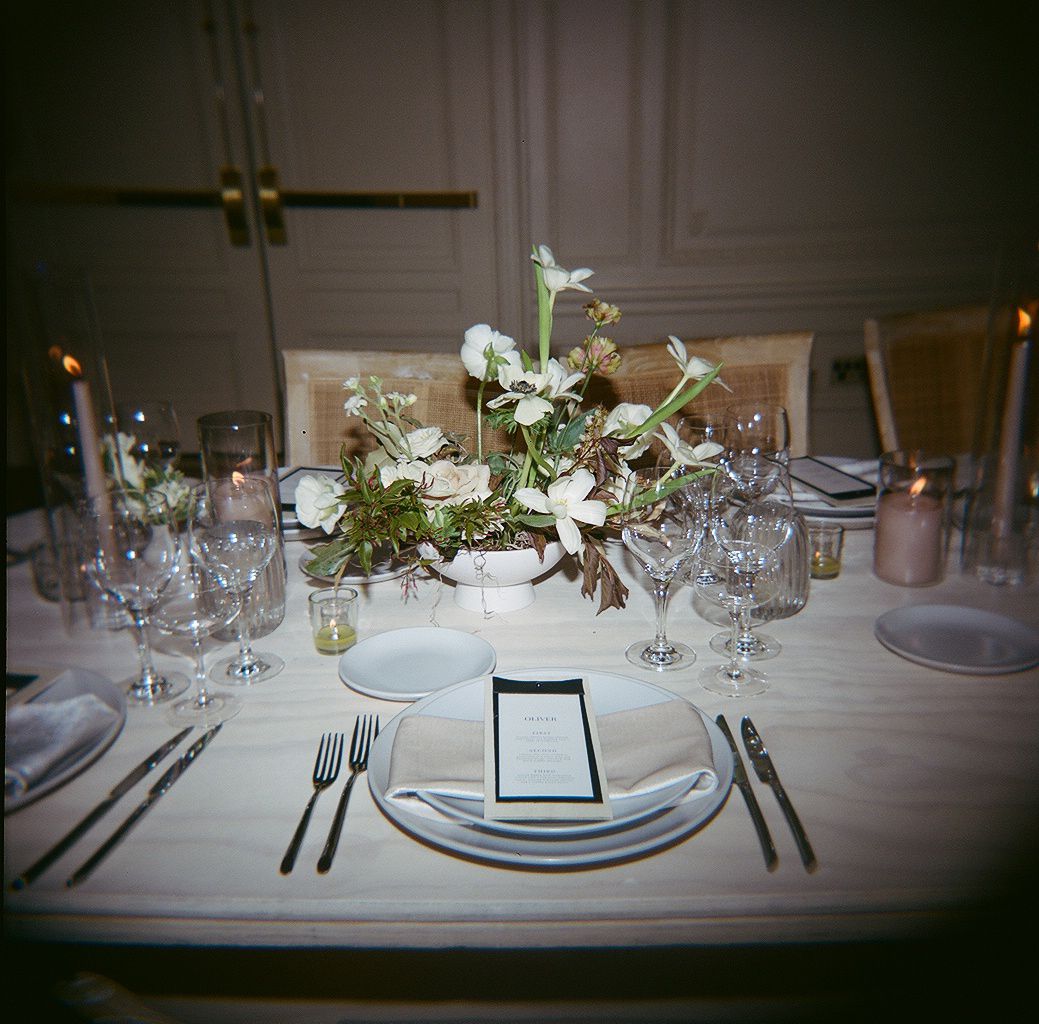 Elegant table settings at a formal dining event with white linens, wine glasses, and delicate floral centerpieces.