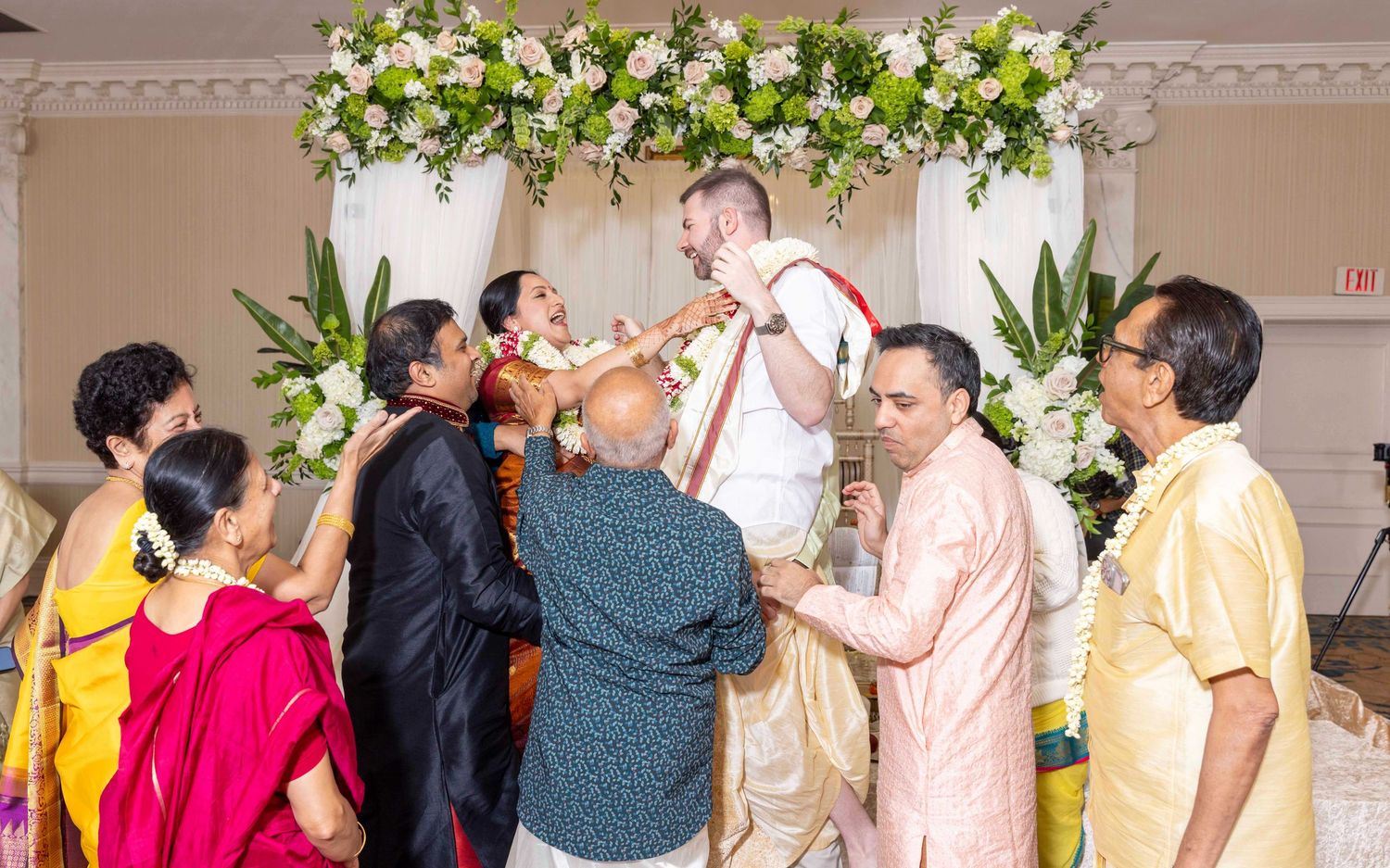 Group celebrating during a traditional ceremony under floral decorations.
