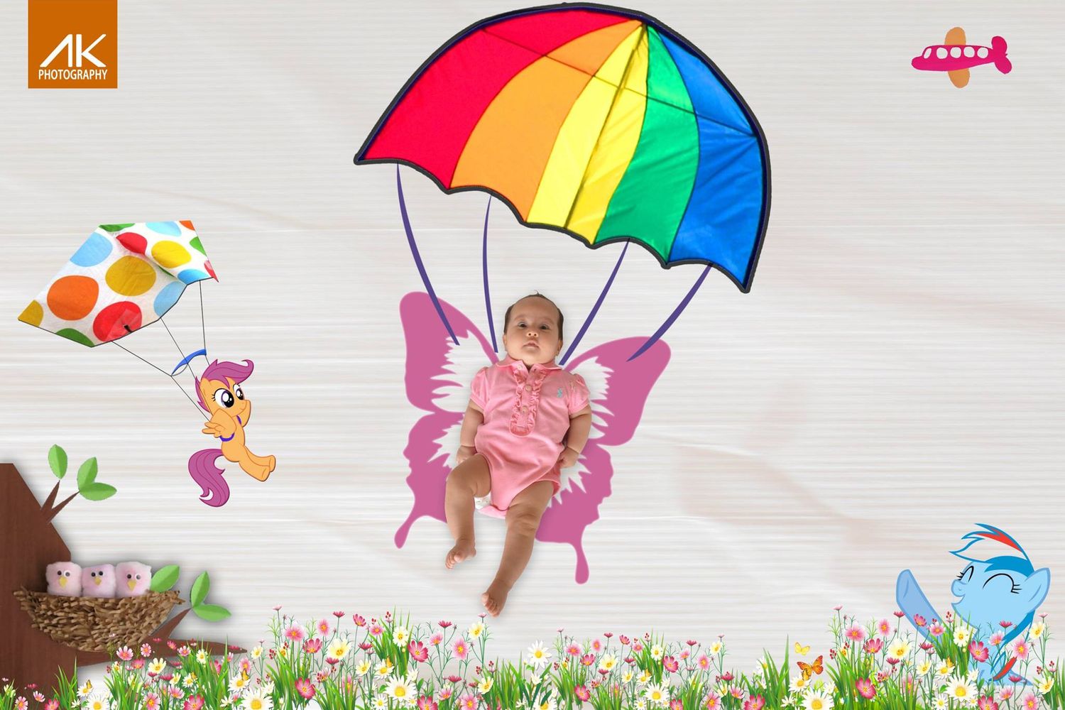 Creative baby portrait with rainbow umbrella and fairy wings against floral background.