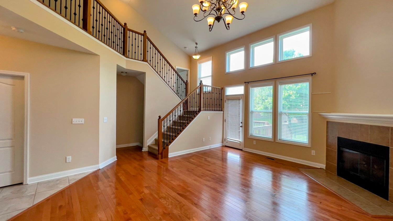 Two-story living room with hardwood floors and elegant staircase.