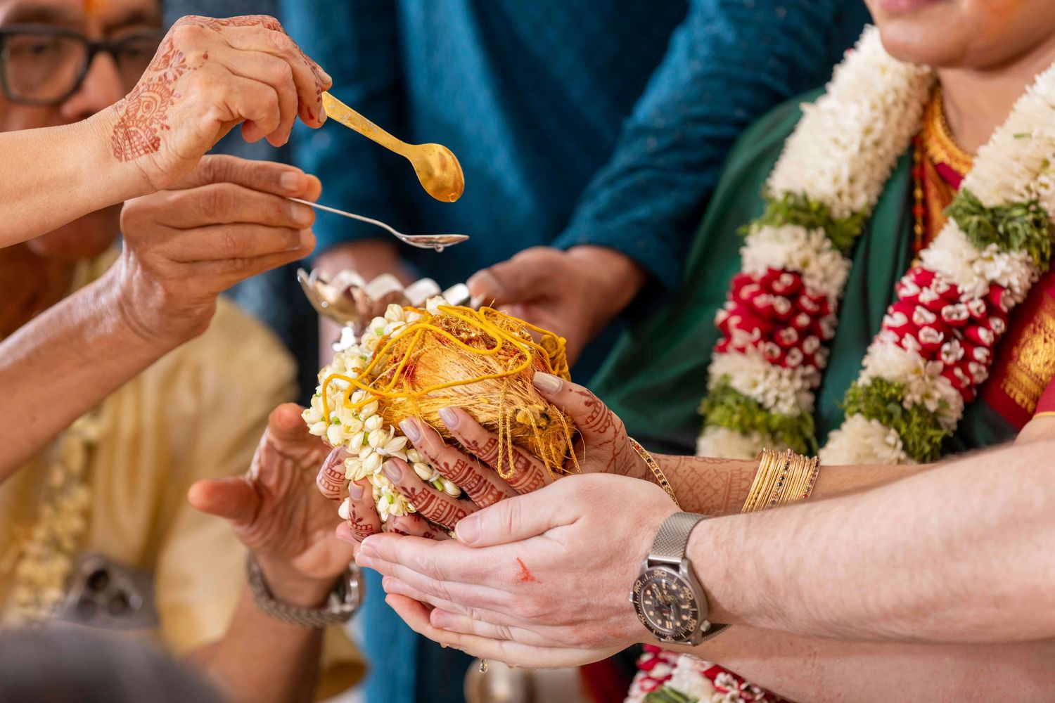 Traditional Indian wedding ceremony ritual showing turmeric paste being applied with decorative floral garlands visible.