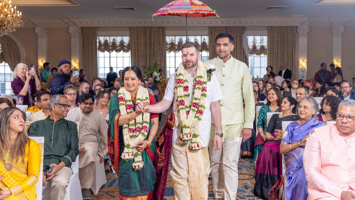 Wedding guests and attendees gather in an elegant venue during a traditional Indian-fusion style ceremony celebration.