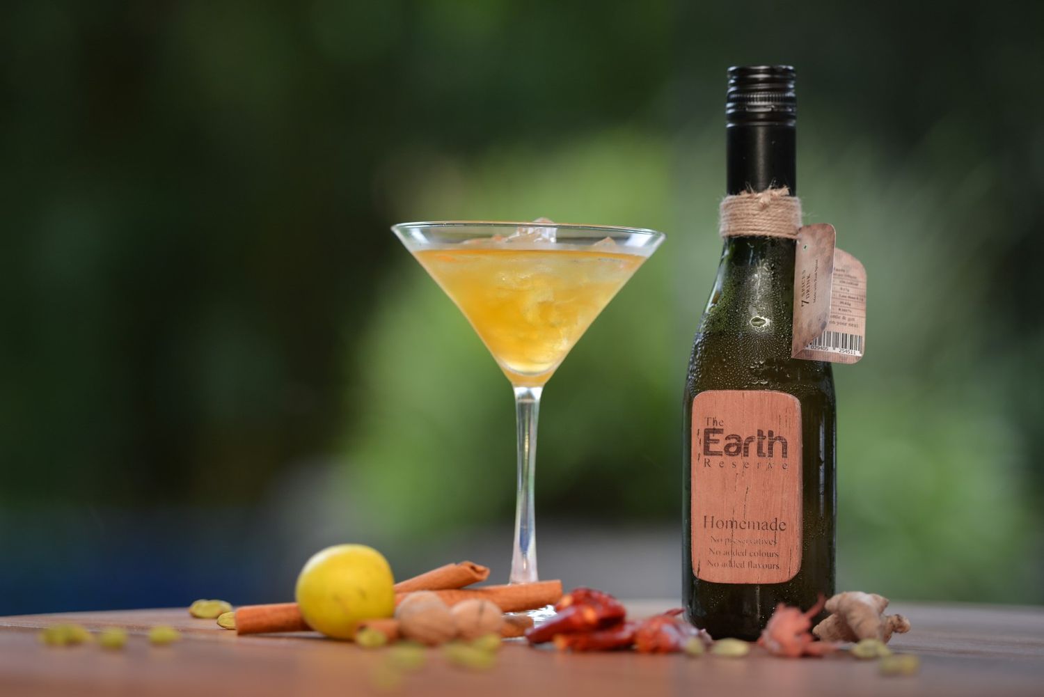 Elegant martini cocktail with bottle of Earth brand liquor in outdoor setting.