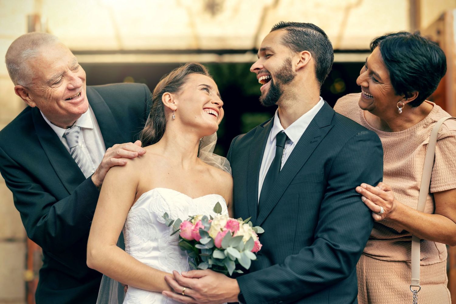 Candid moment of newlyweds and wedding party members sharing laughter together.