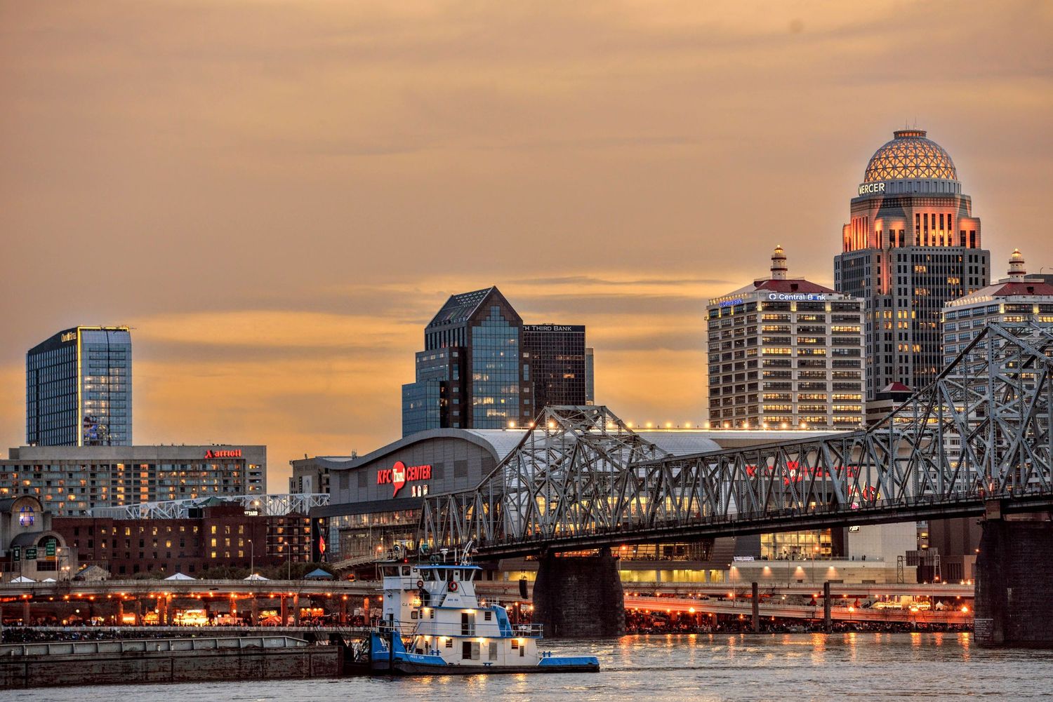Louisville skyline at dusk with Second Street Bridge and Ohio River in foreground.