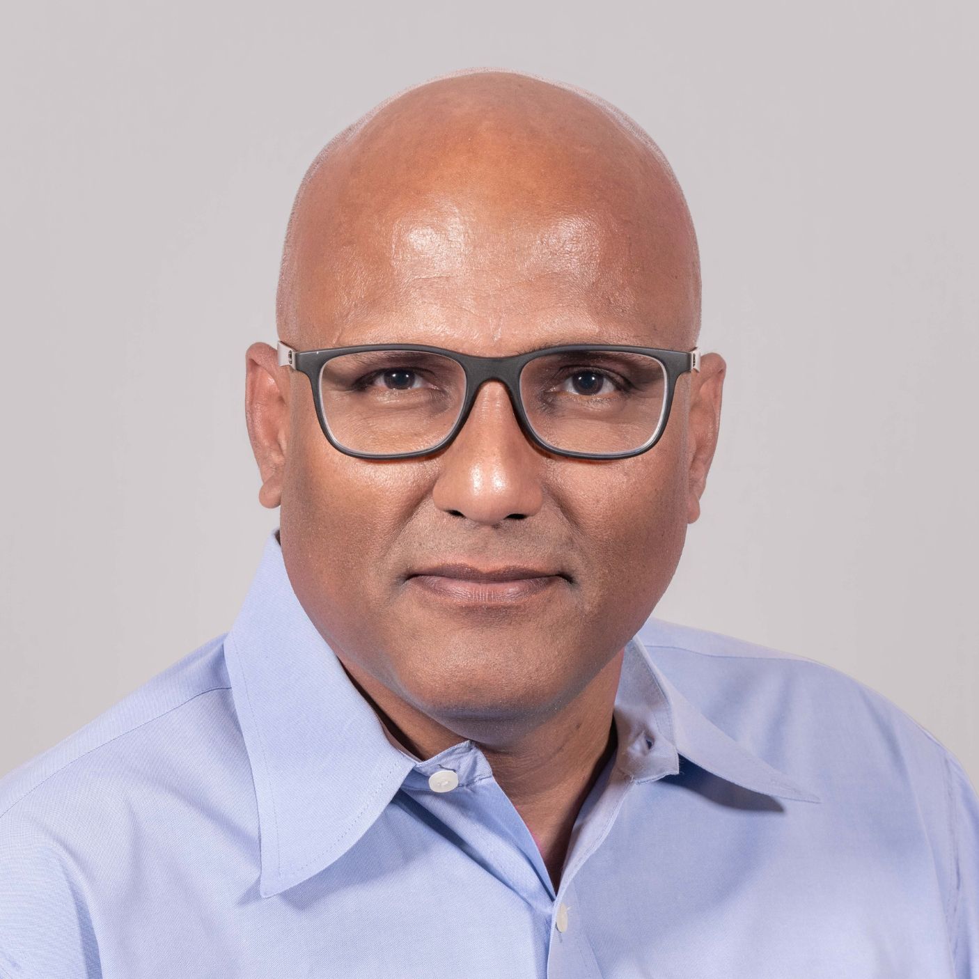 Professional corporate headshot against grey background.