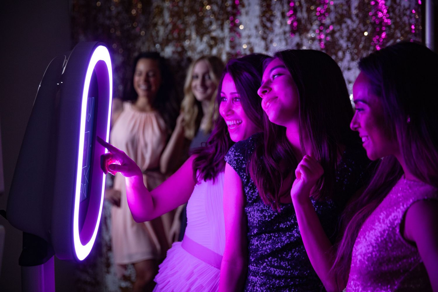 Group enjoying a photo booth moment illuminated by purple LED lighting.