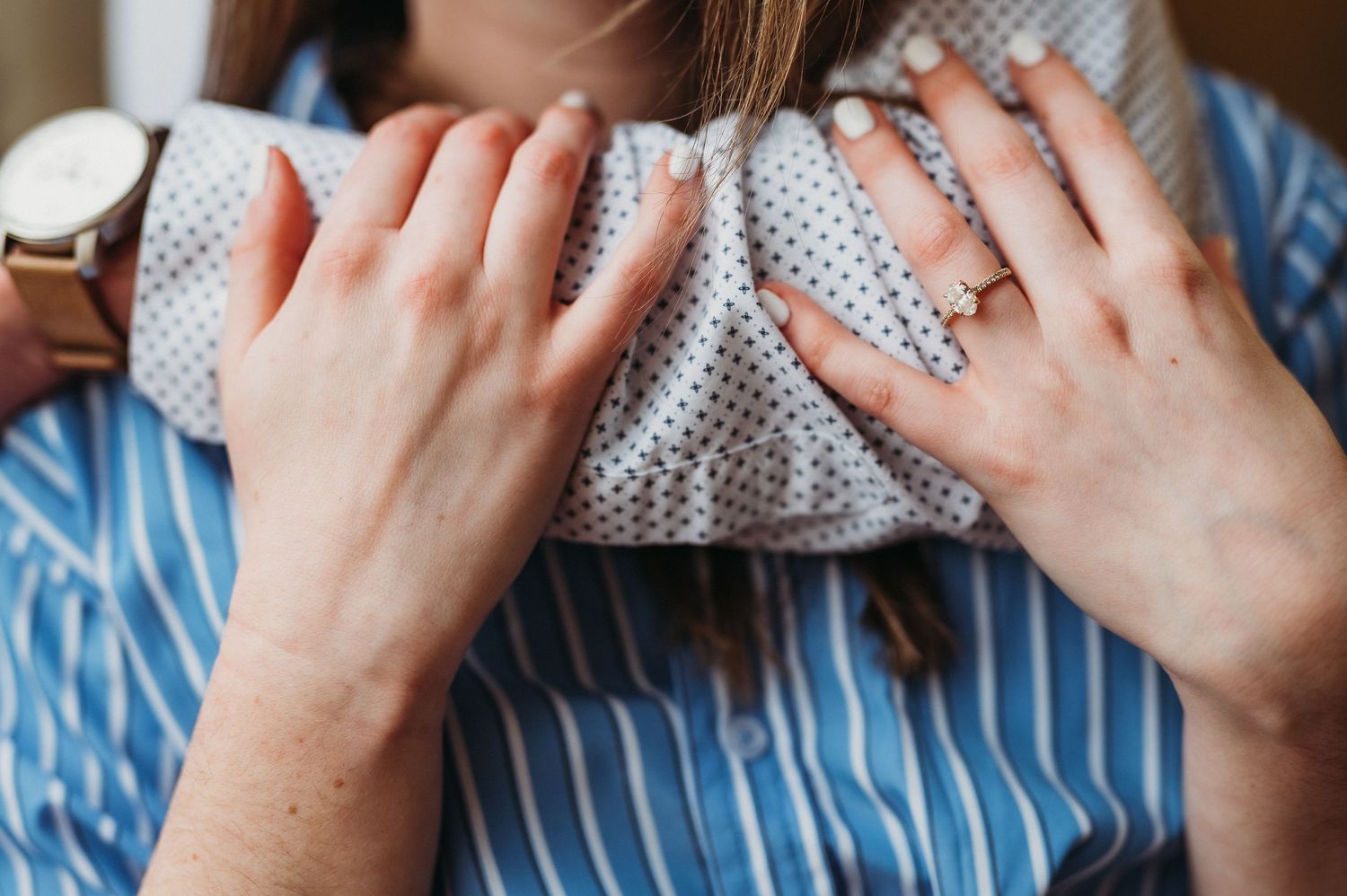 Hands hold gray knitted fabric while sitting on blue and white striped fabric.