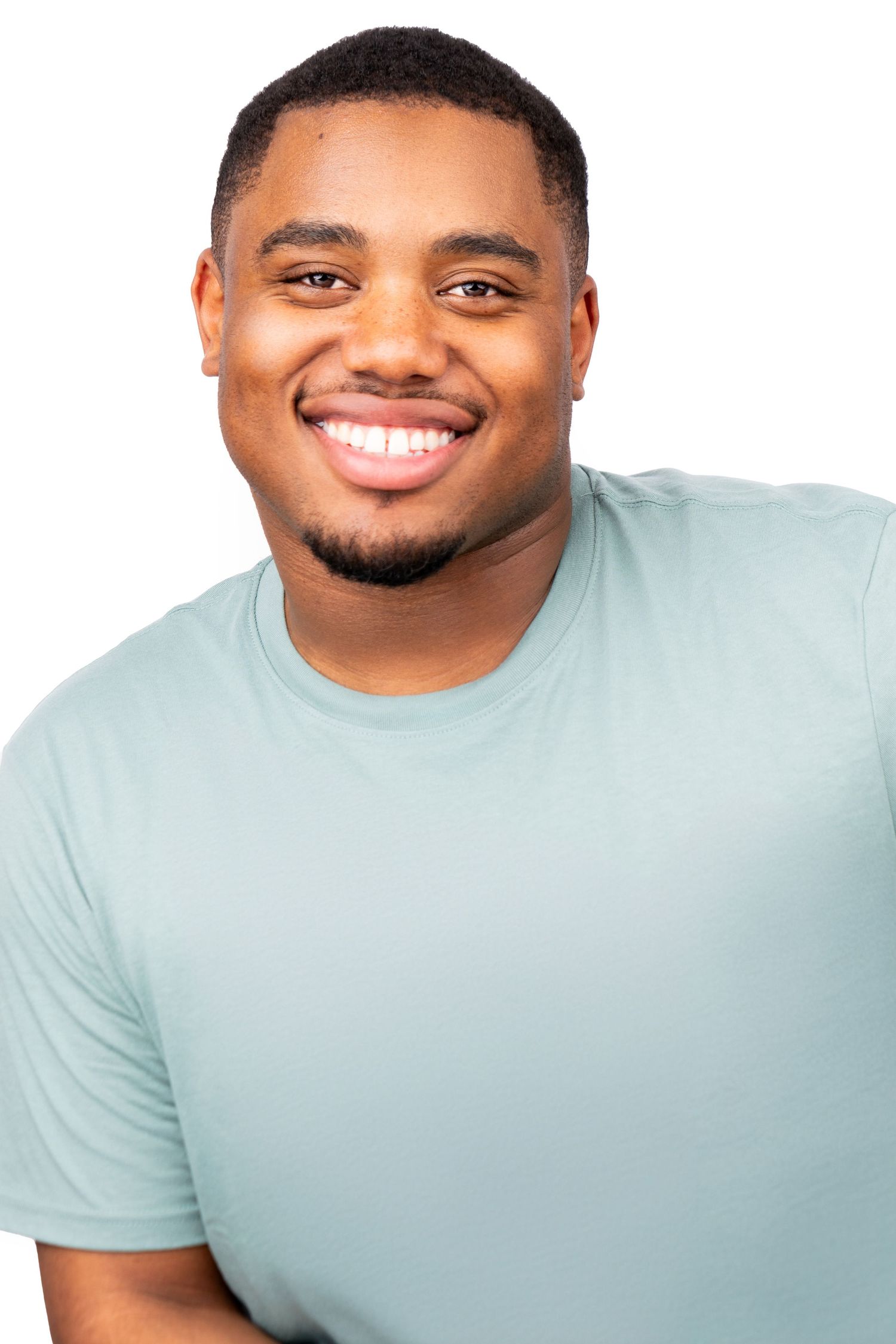 Smiling person wearing a light mint green t-shirt against white background in professional headshot style portrait.