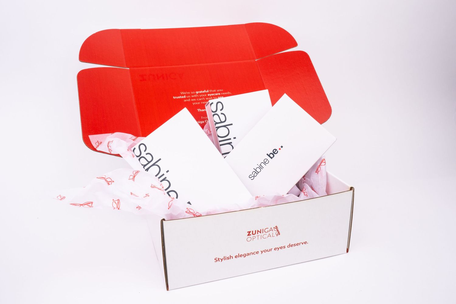 Open red subscription box filled with white tissue paper and product packaging visible inside.