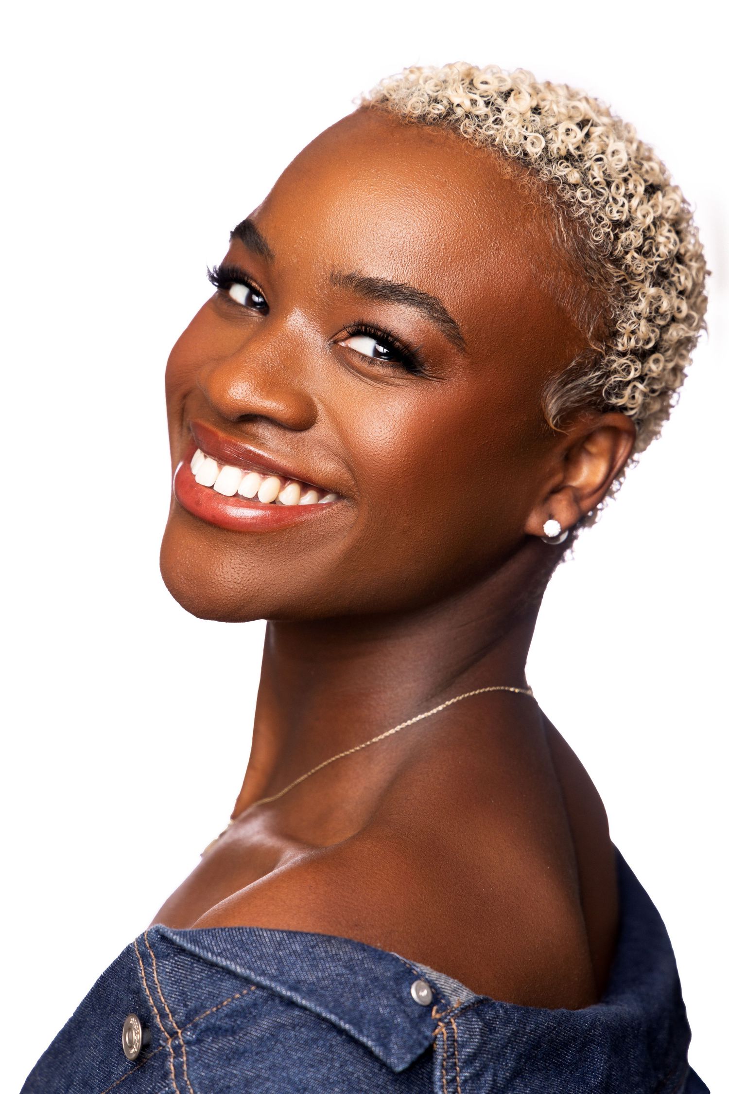Portrait series of a person with bleached blonde short hair and glowing skin smiling against dark background in four poses.