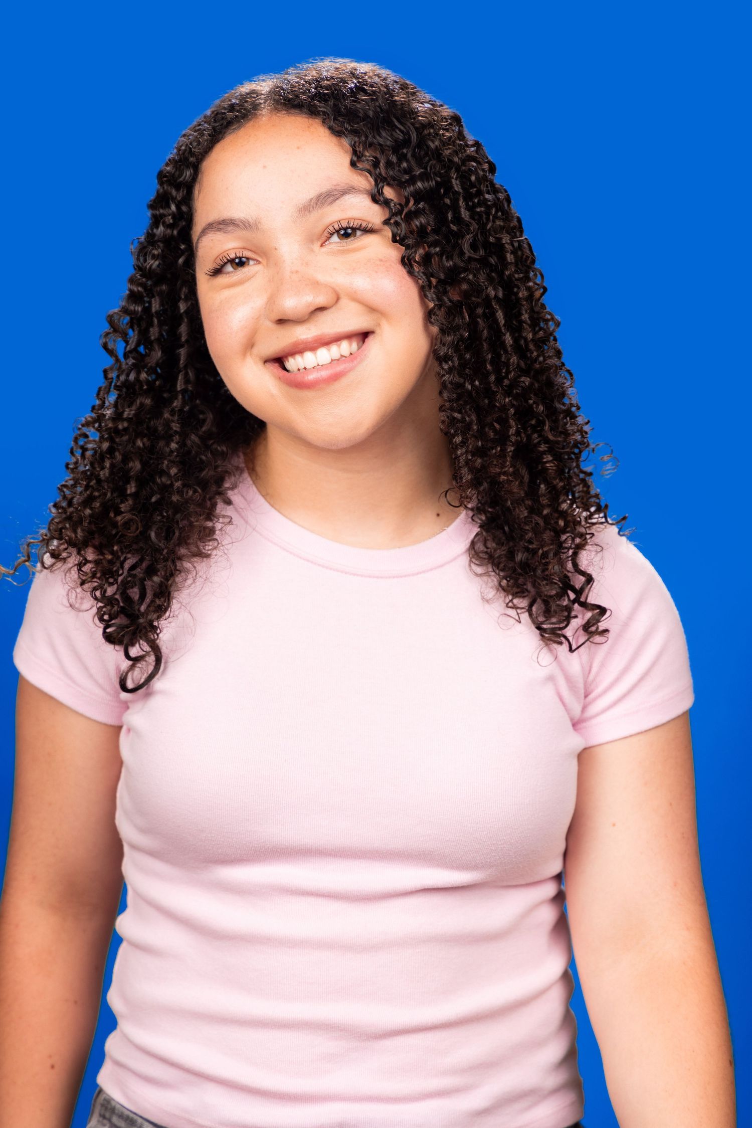 A person in a light pink t-shirt with curly dark hair shown in a sequence of six photos against a bright blue background.