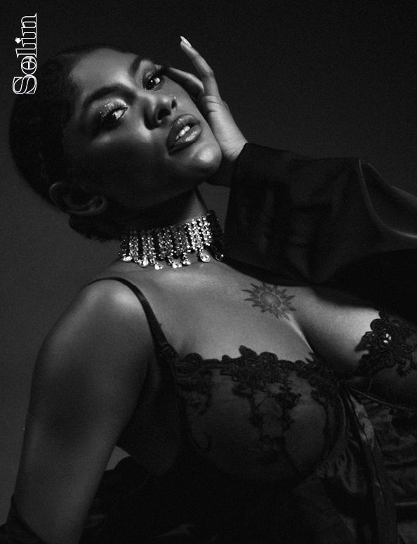 Artistic black and white portrait featuring elegant jewelry and lace detailing in dramatic lighting.