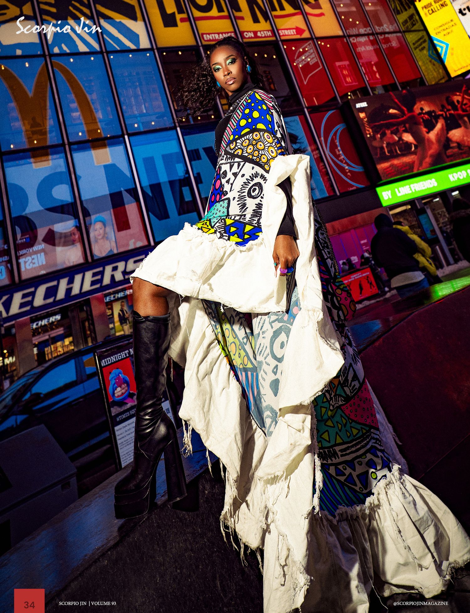 Fashion model poses in avant-garde white dress with colorful accents against wall of retail store signs and displays.