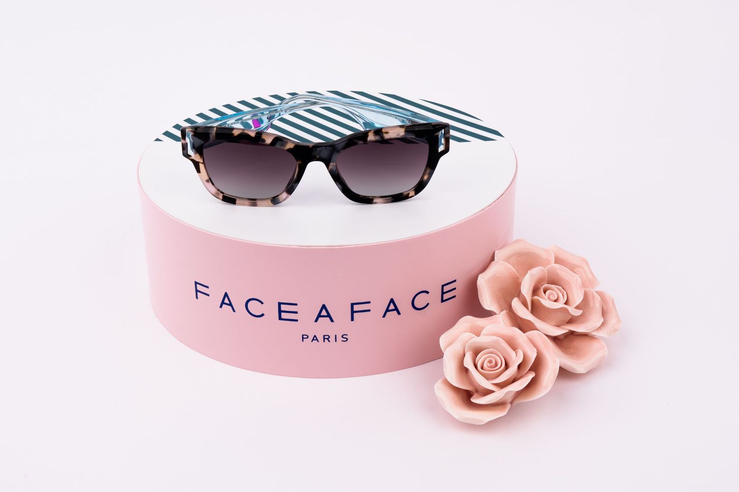 Black and white striped sunglasses on a pink Face A Face Paris box with two pink decorative roses.