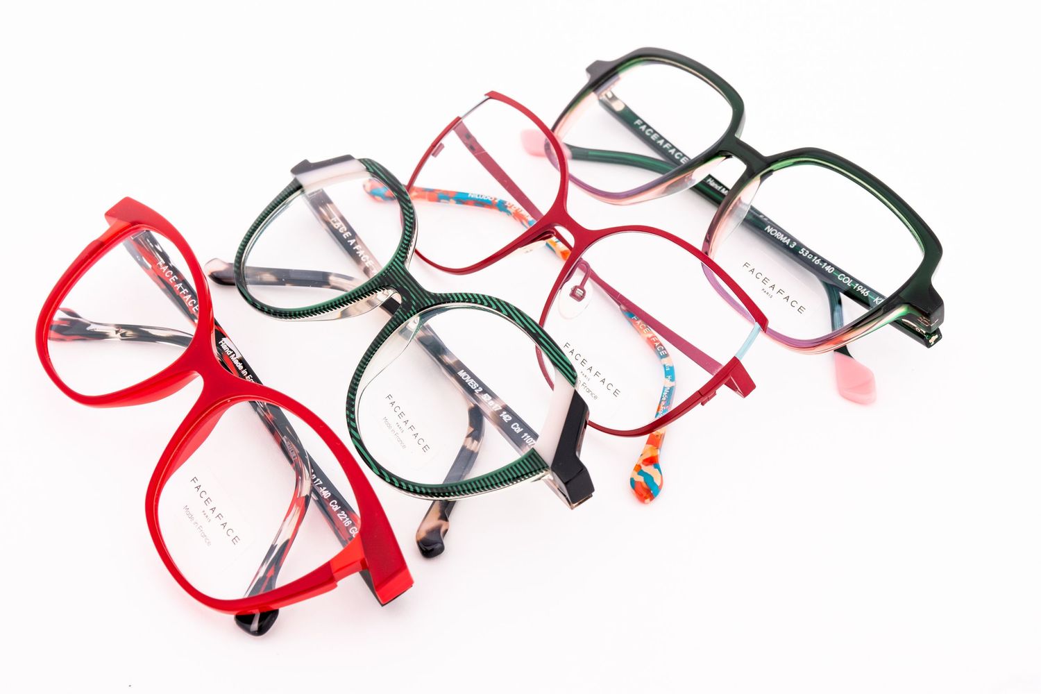 Collection of modern eyeglass frames in red and black colors arranged in a row on white background.