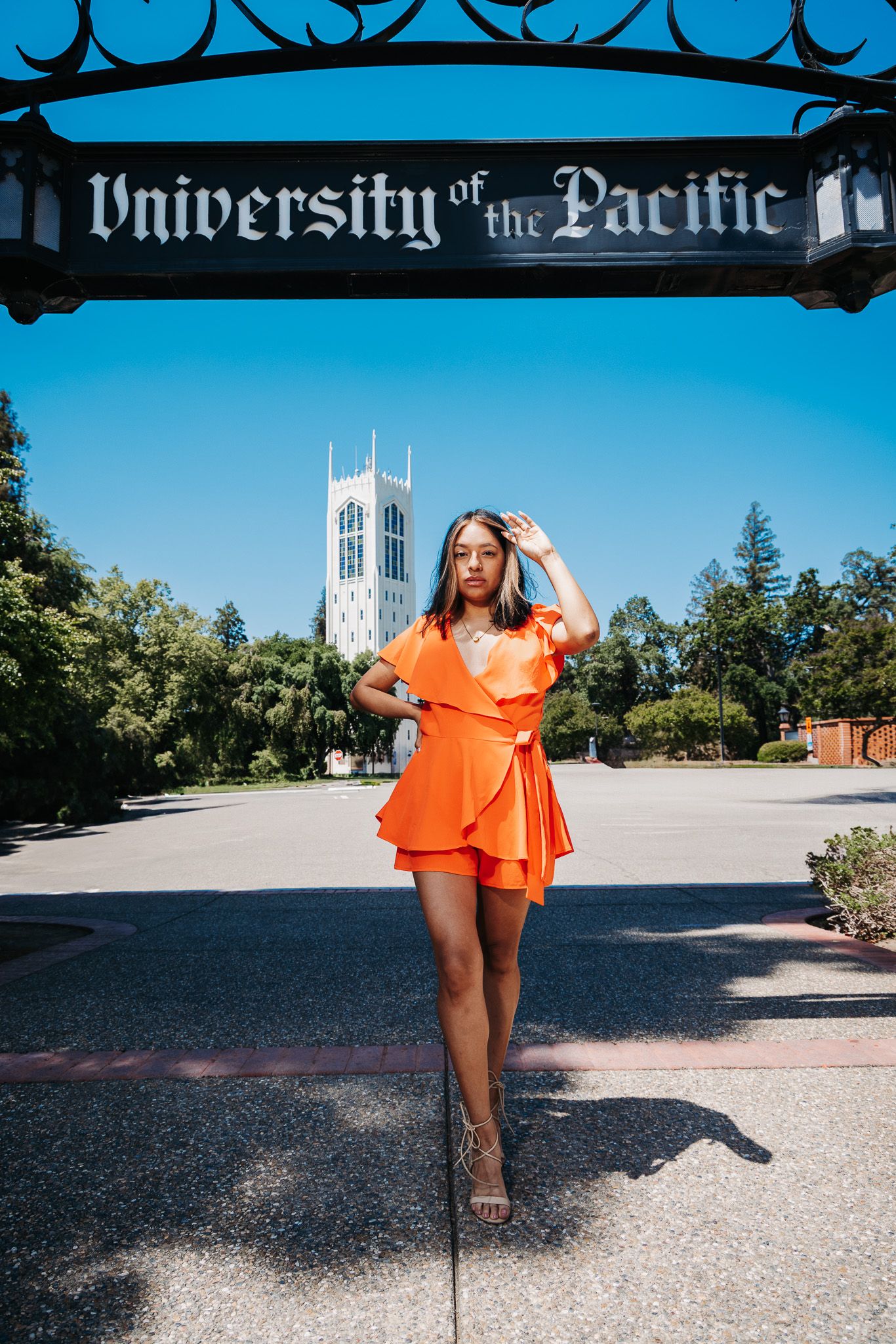 A bright orange summer romper photographed in front of University of the Pacific's iconic tower on a sunny day.