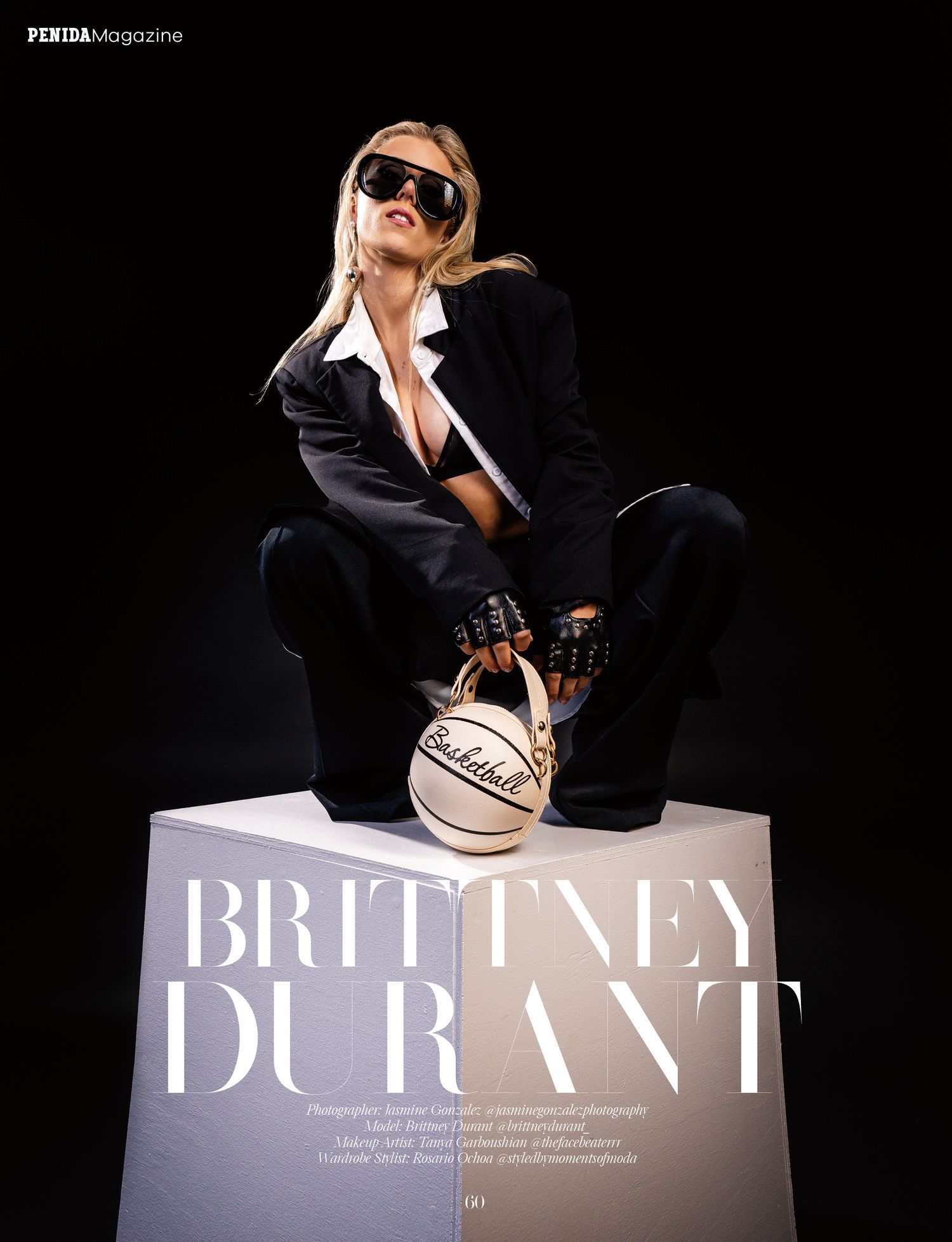 Fashion editorial photo shows a figure in black outfit and sunglasses posing with a basketball on a cube pedestal.