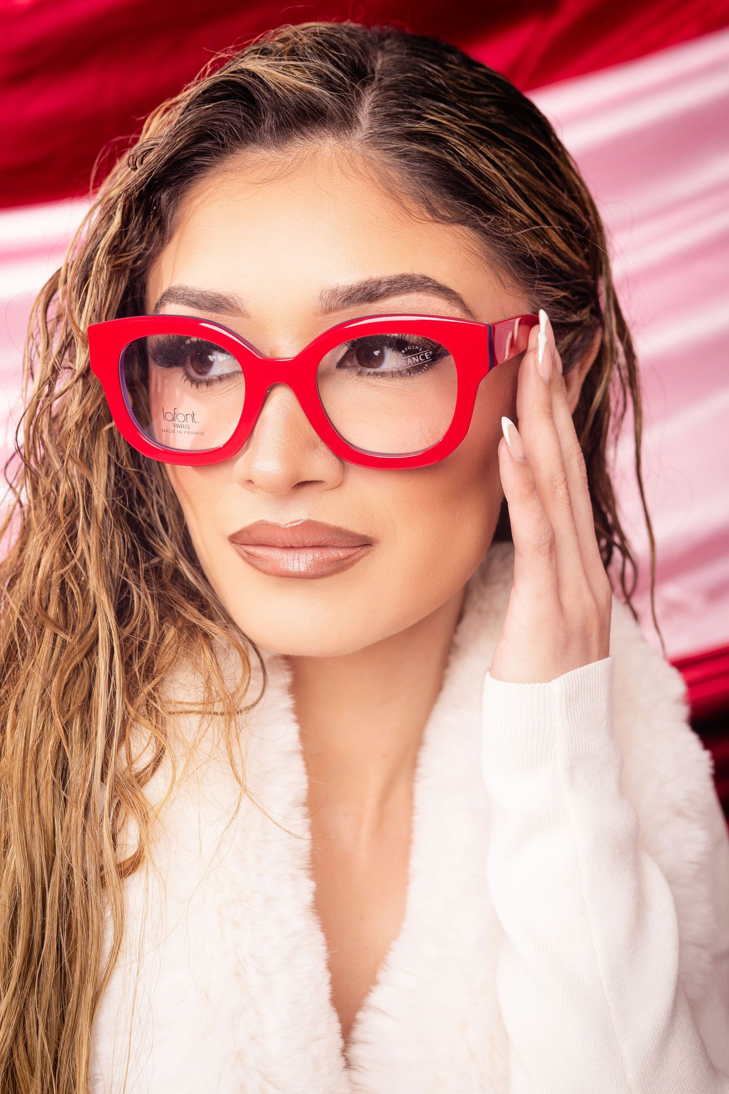 Red designer eyeglasses showcased on display with dramatic lighting.