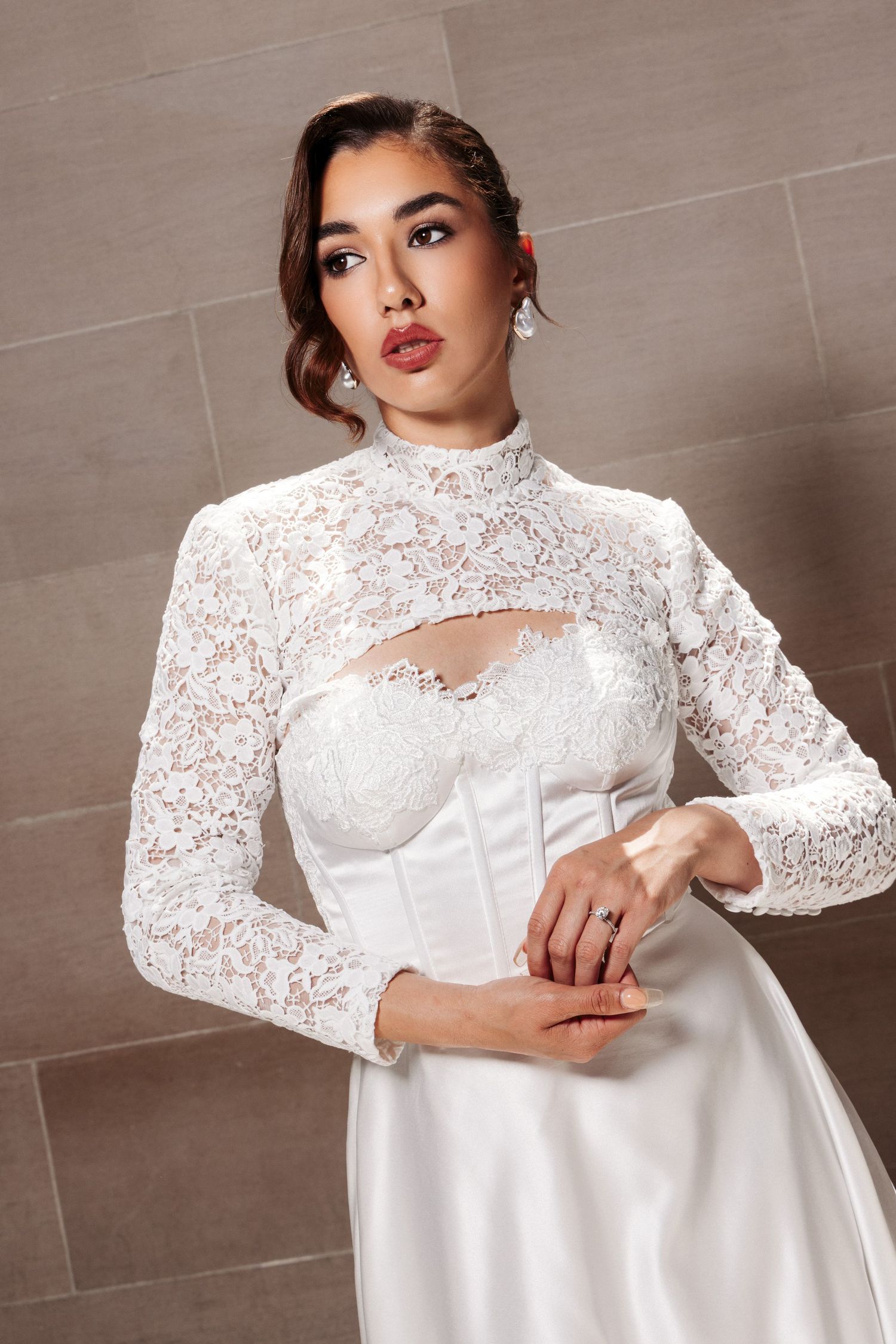 Close up of white lace wedding dress with high neckline, corset bodice and intricate floral lace details.