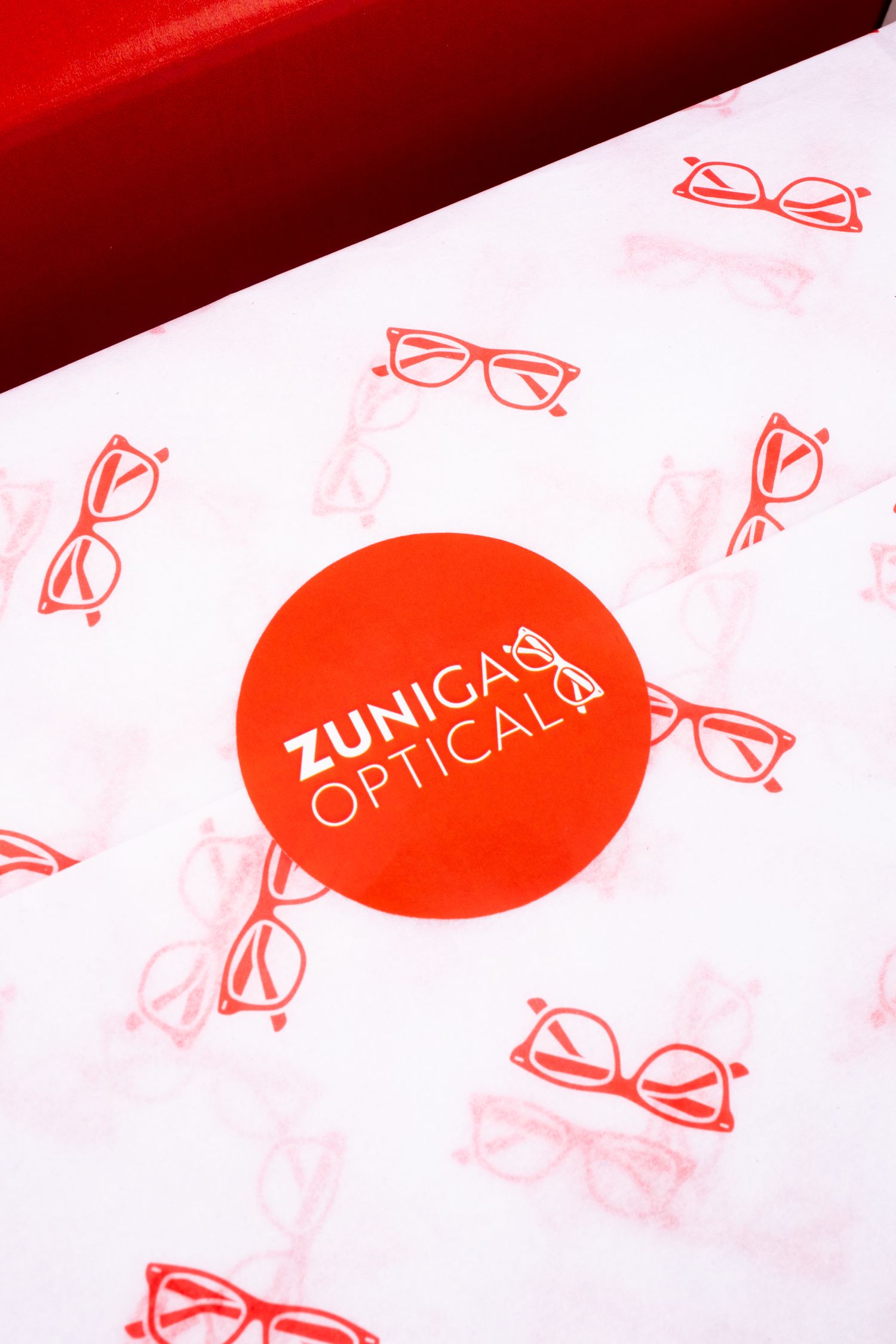 White tissue paper with red eyeglass icons and Zuniga Optical branding.