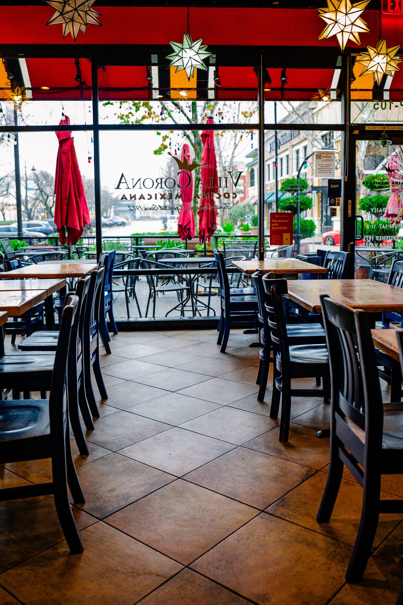Empty cafe interior with dark wooden chairs, red umbrellas, and decorative star lights hanging from the ceiling.