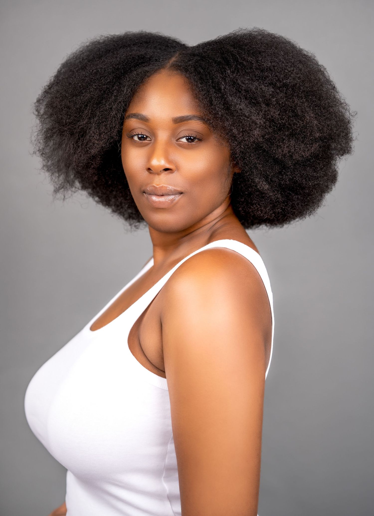 Beautiful natural afro hairstyle styled in a voluminous symmetrical shape against a gray background.
