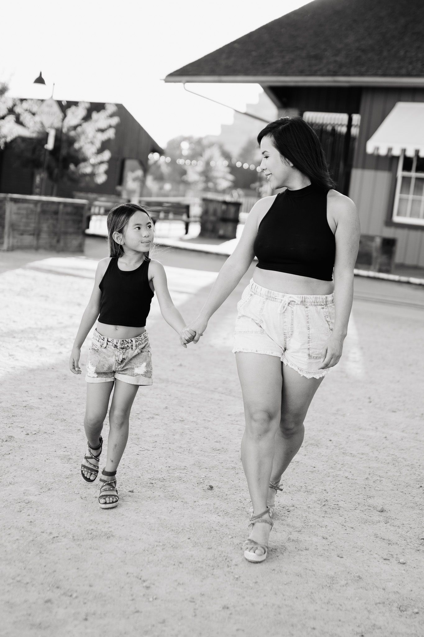 A black and white photo shows a heartwarming moment between a parent and child holding hands while walking outdoors.