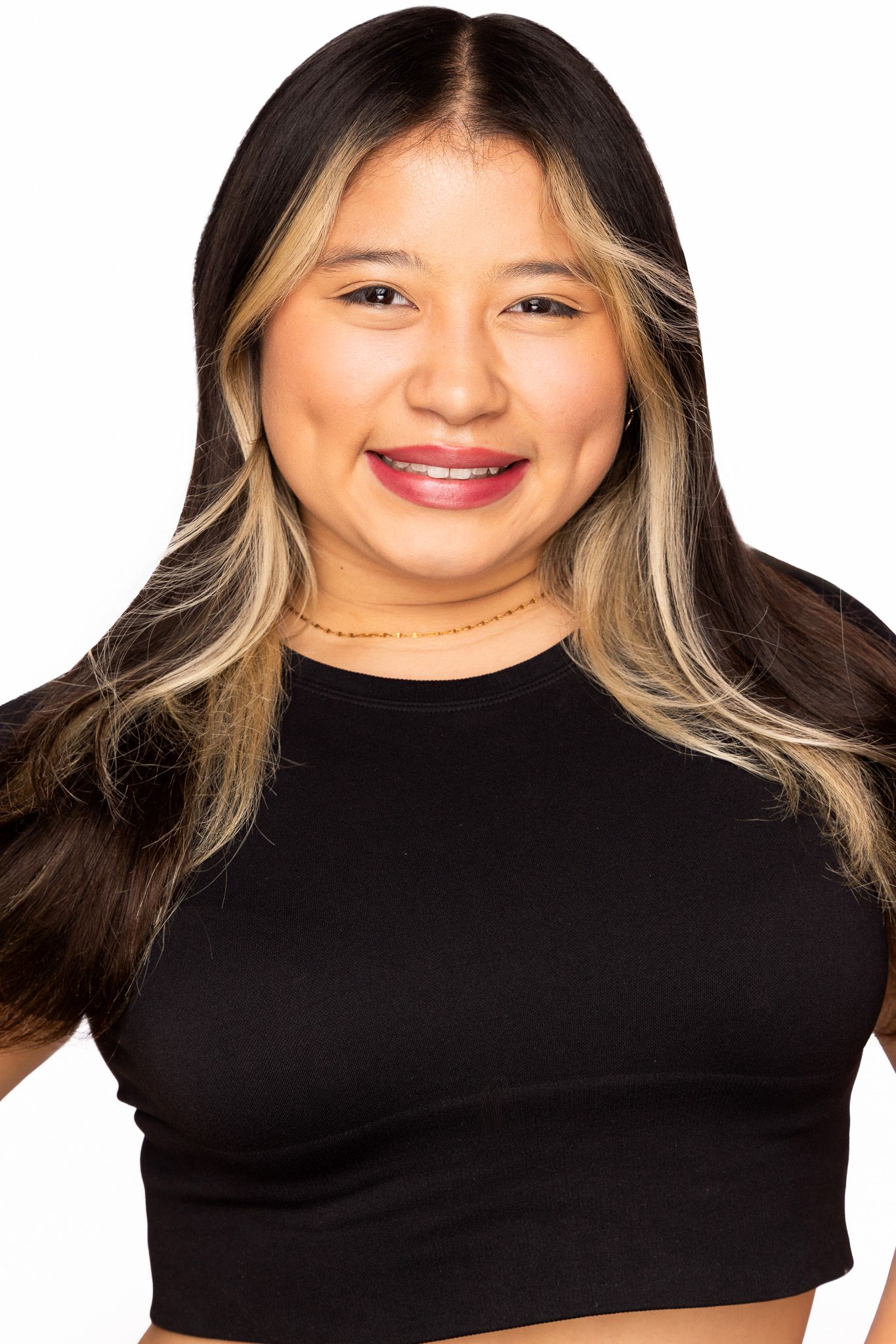 Portrait of a smiling person wearing a black crop top and styled blonde ombre hair against a white background.
