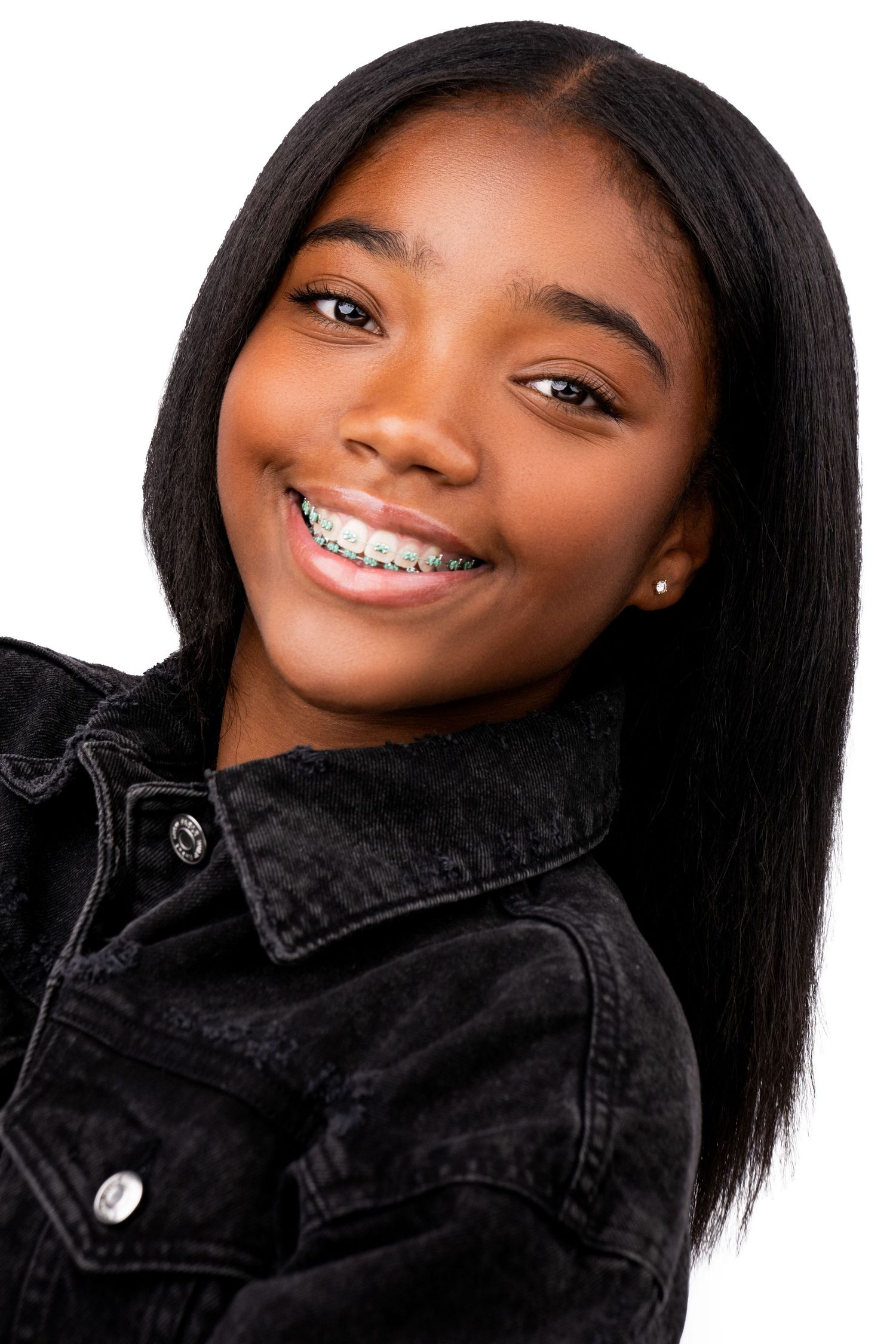Portrait of someone with a bright smile in a black denim jacket against a white background.