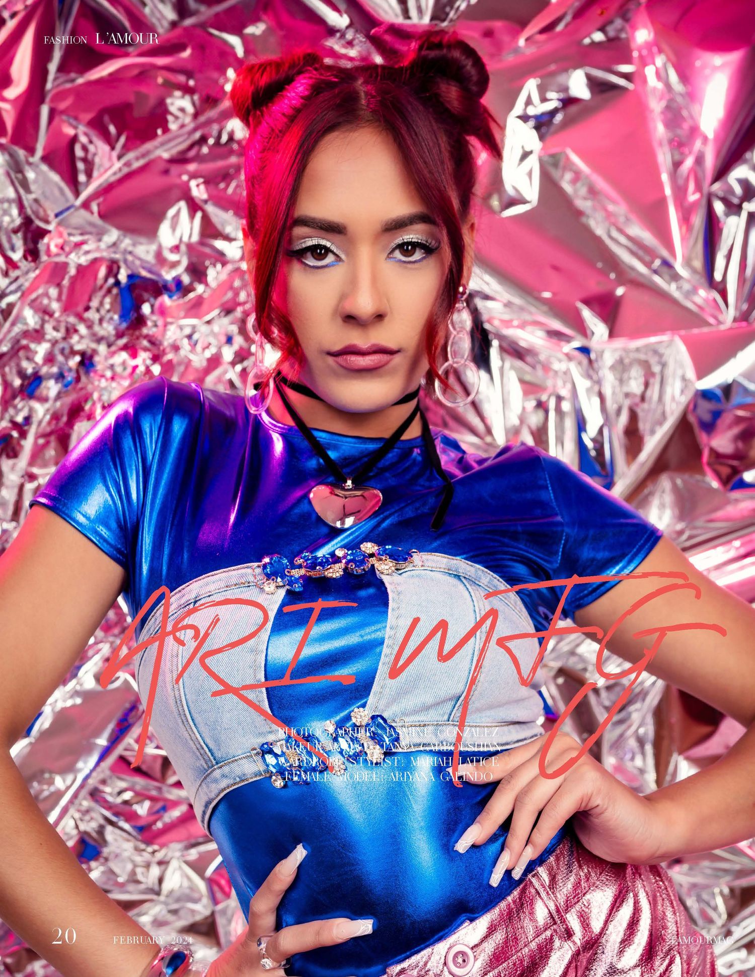 Fashion model in metallic blue top poses against shimmering pink foil backdrop with dramatic lighting and styling.