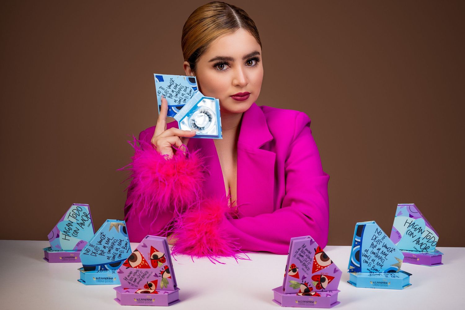 Person in bright pink blazer sitting at table with blue and purple decorated triangular display items.