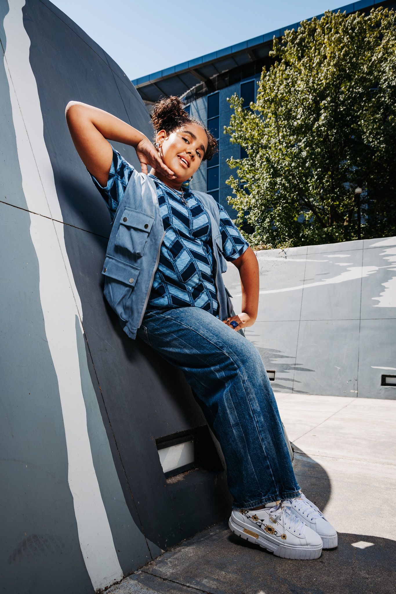 Person in denim outfit sitting on white ledge wearing white sneakers at skate park in dynamic angles.